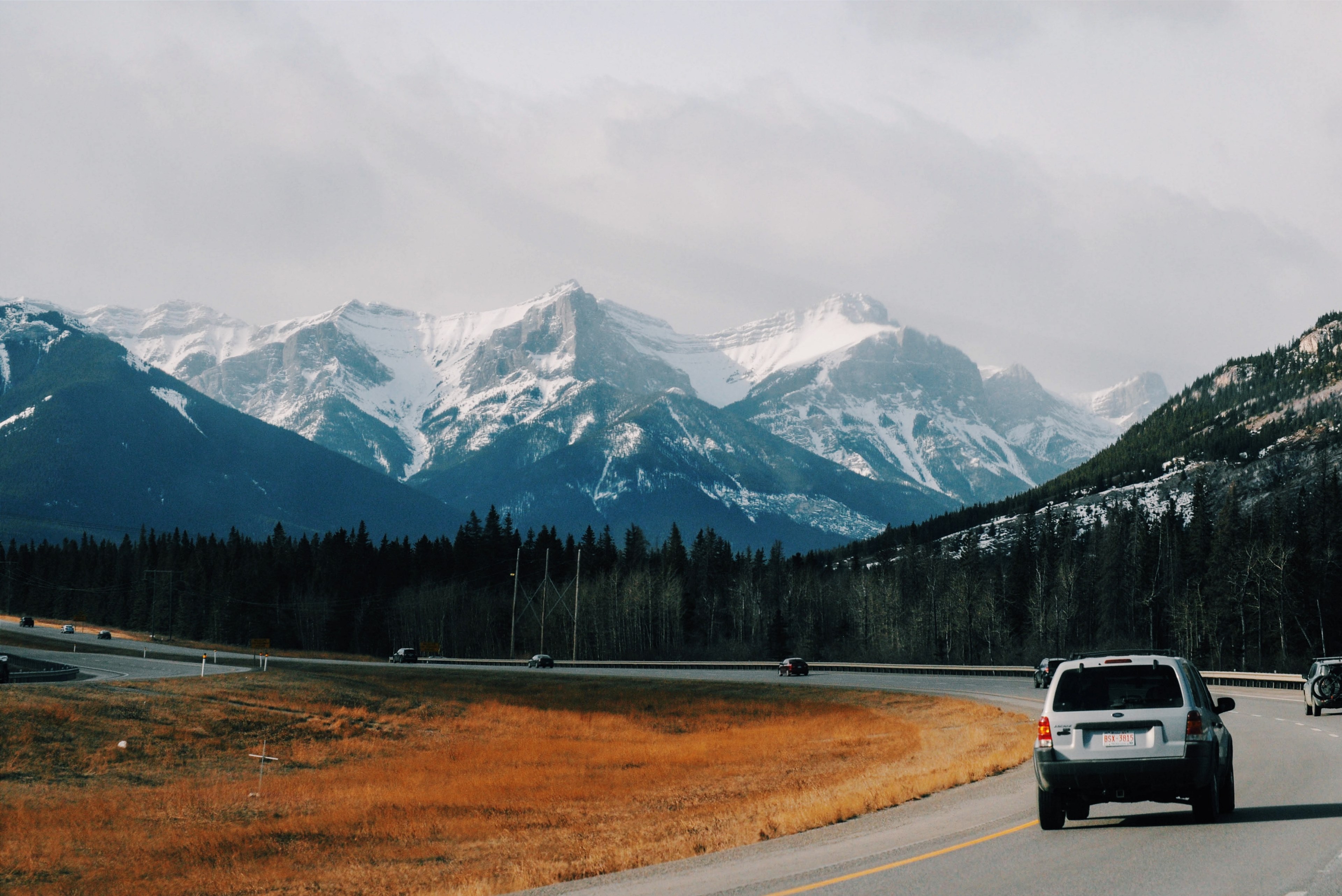 gray suv driving along a bended road with trees and snowy mountains in the backdrop banff, gray suv mountains banff 4k, HD Wallpaper