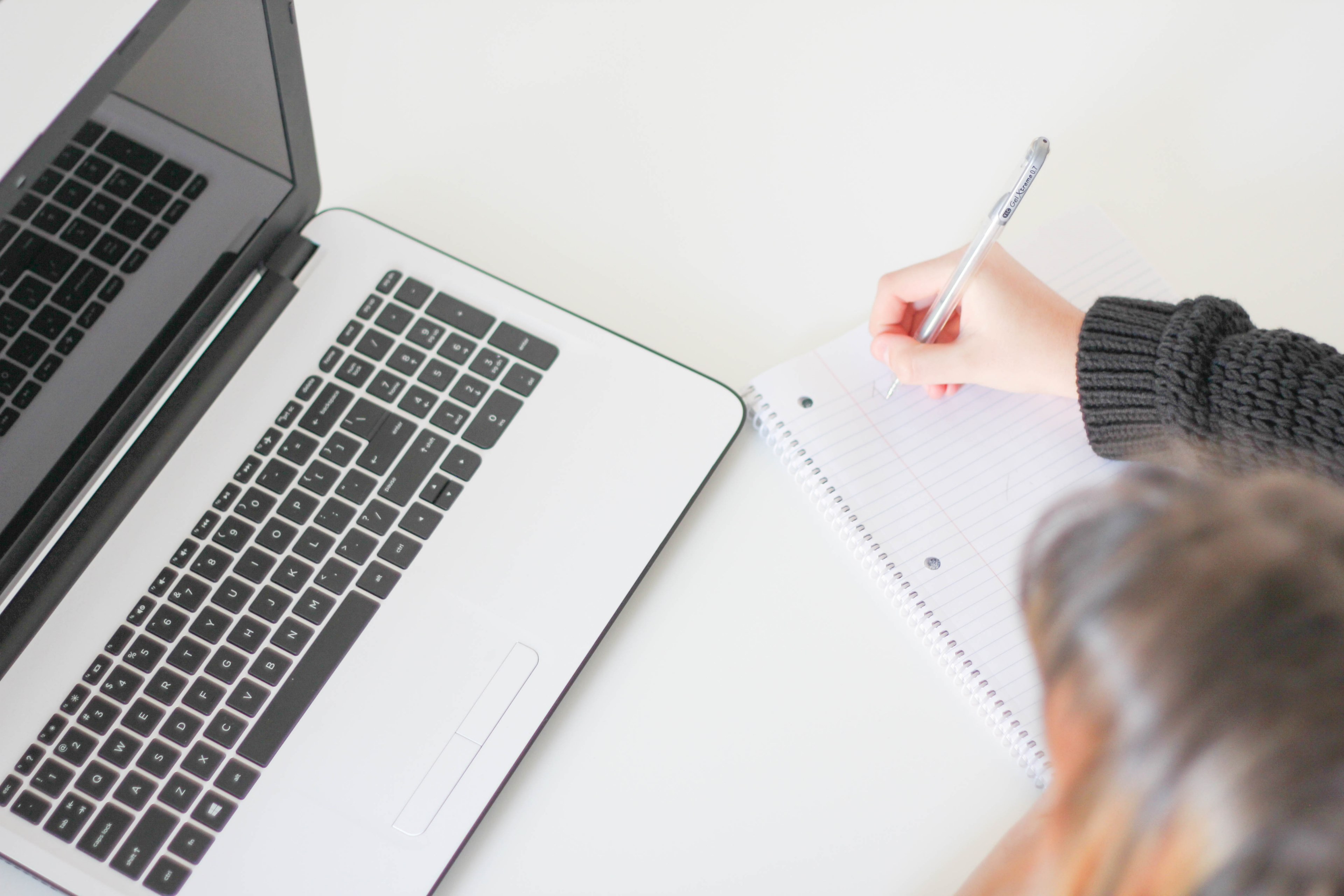 a woman taking notes in a large notebook next to a laptop, brainstorming 4k, HD Wallpaper