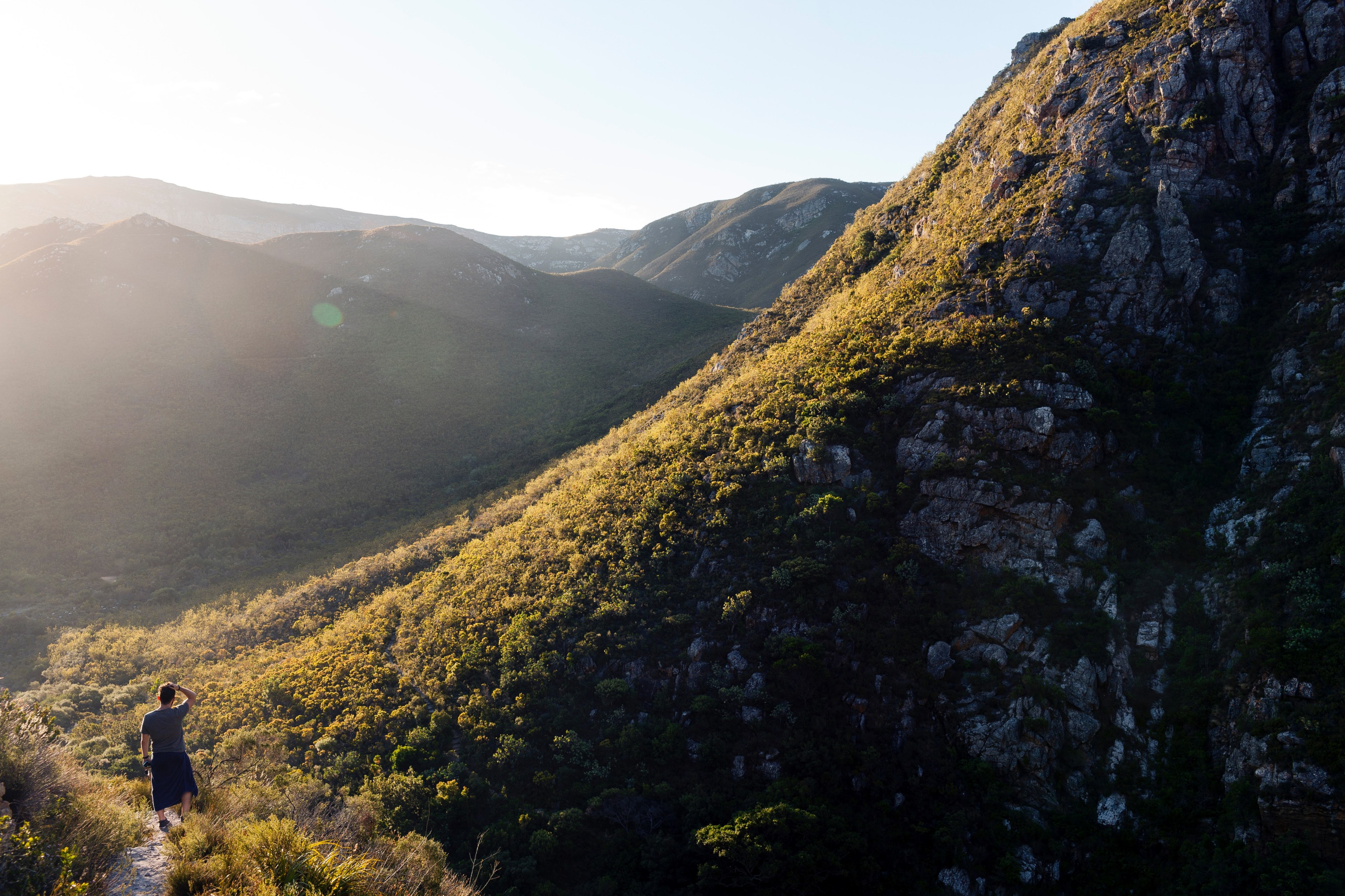 a man walking on a beaten path at the foot of a rocky slope, a walk in the hills on a sunny day 4k, HD Wallpaper