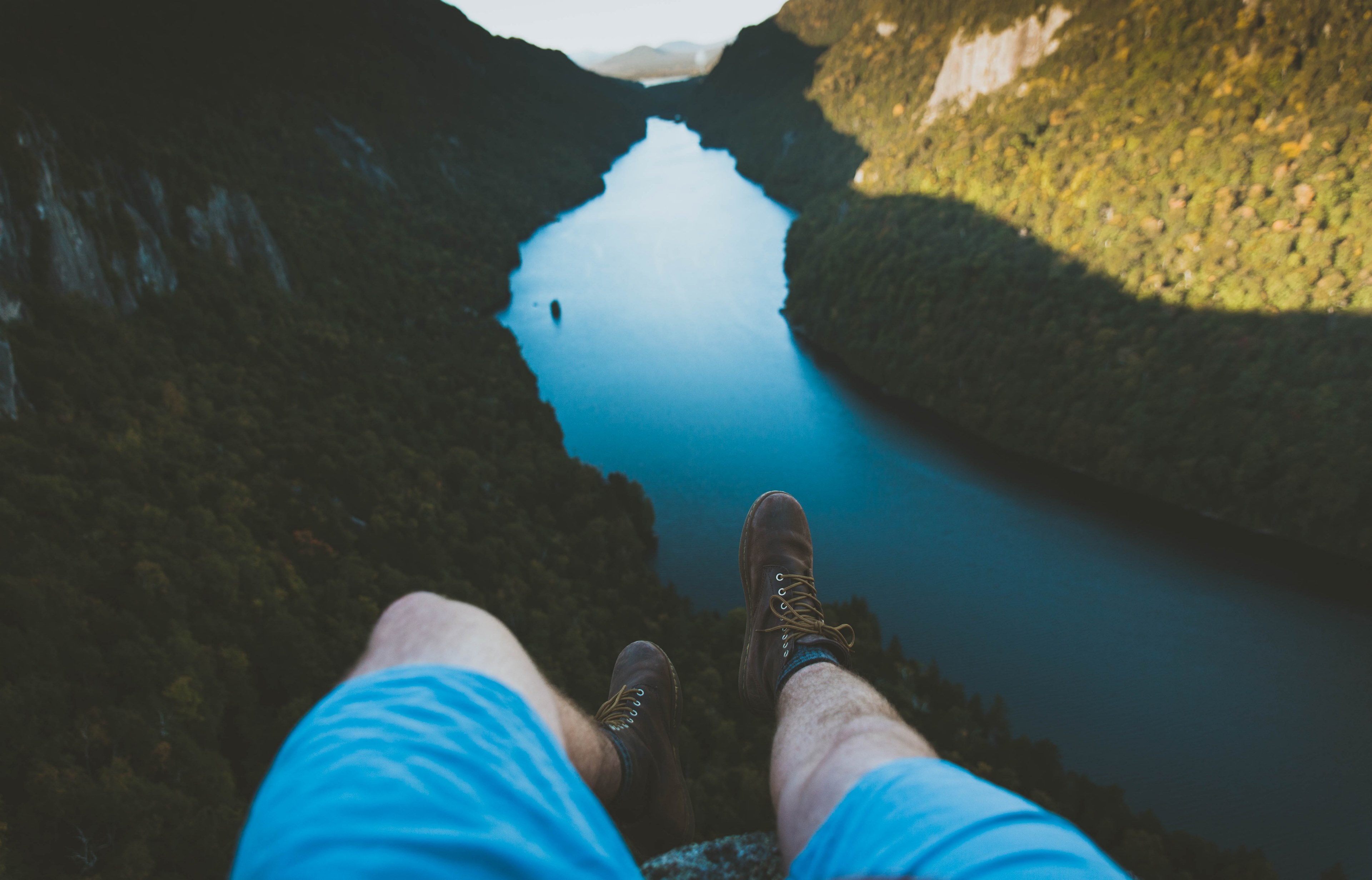 a man sits on a ledge above the river and forest with his legs in view, _sitting above a mountain river 4k, HD Wallpaper