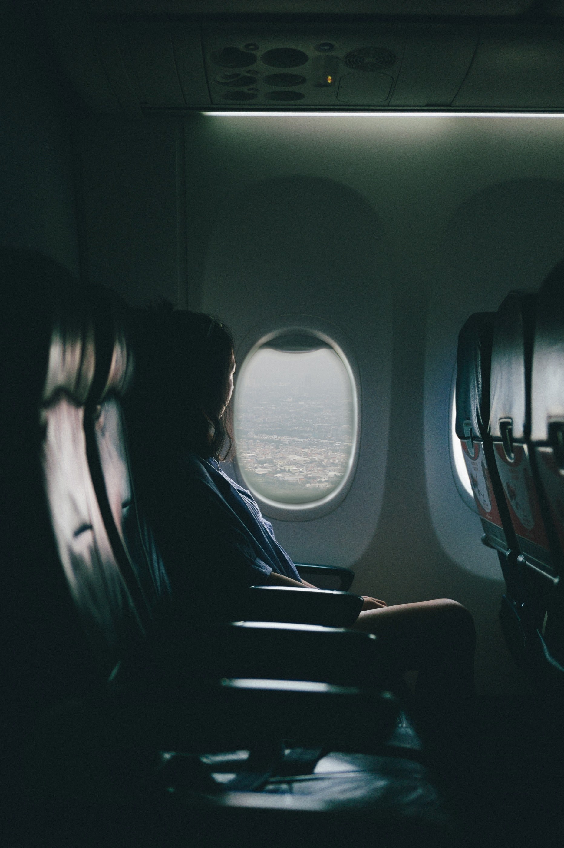 a woman looking out of an airplane window while flying over a city, woman by an airplane window 4k, Phone HD Wallpaper
