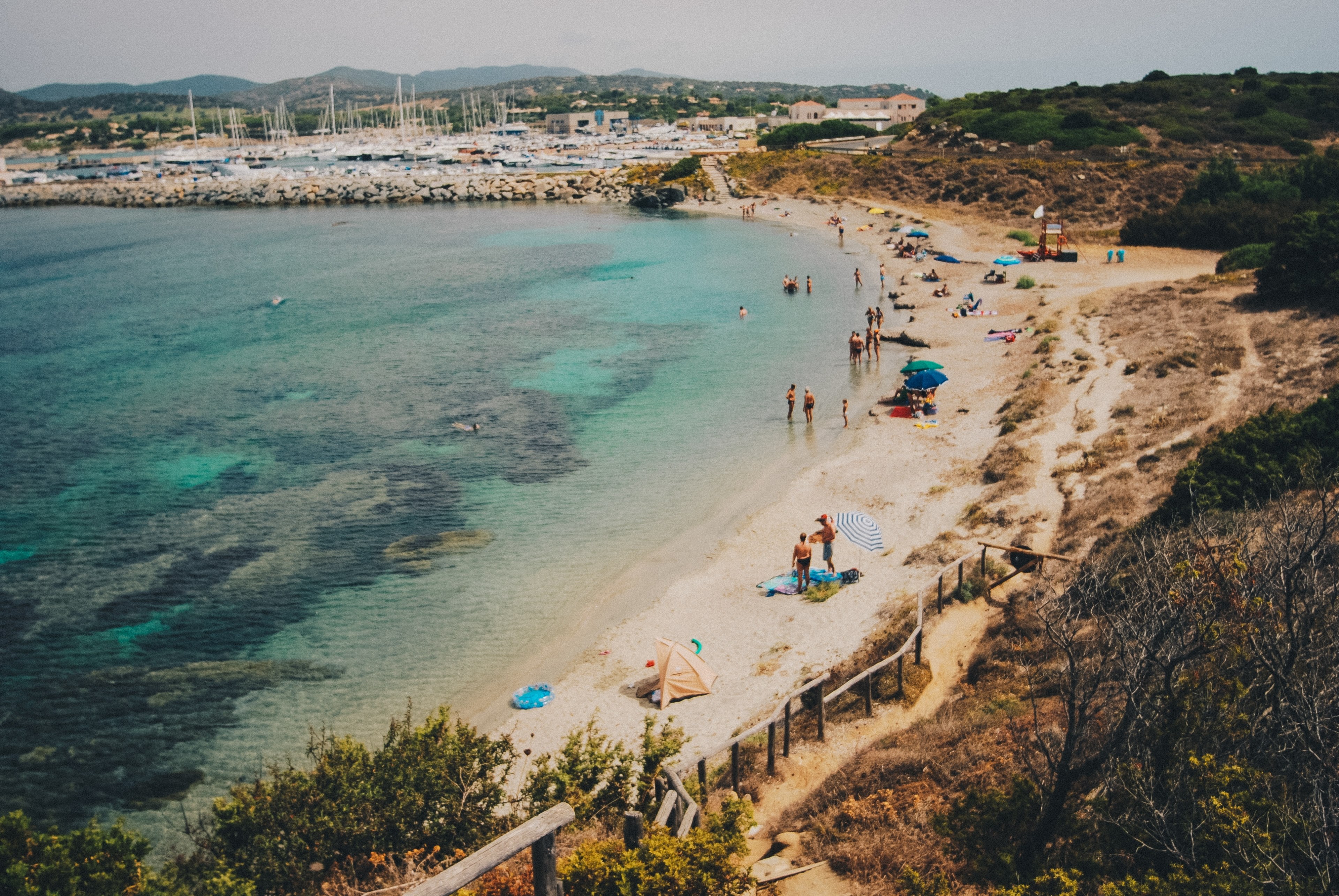 a group of tourists vacationing on a small beach near a waterfront in cagliari, vacation cove 4k, HD Wallpaper