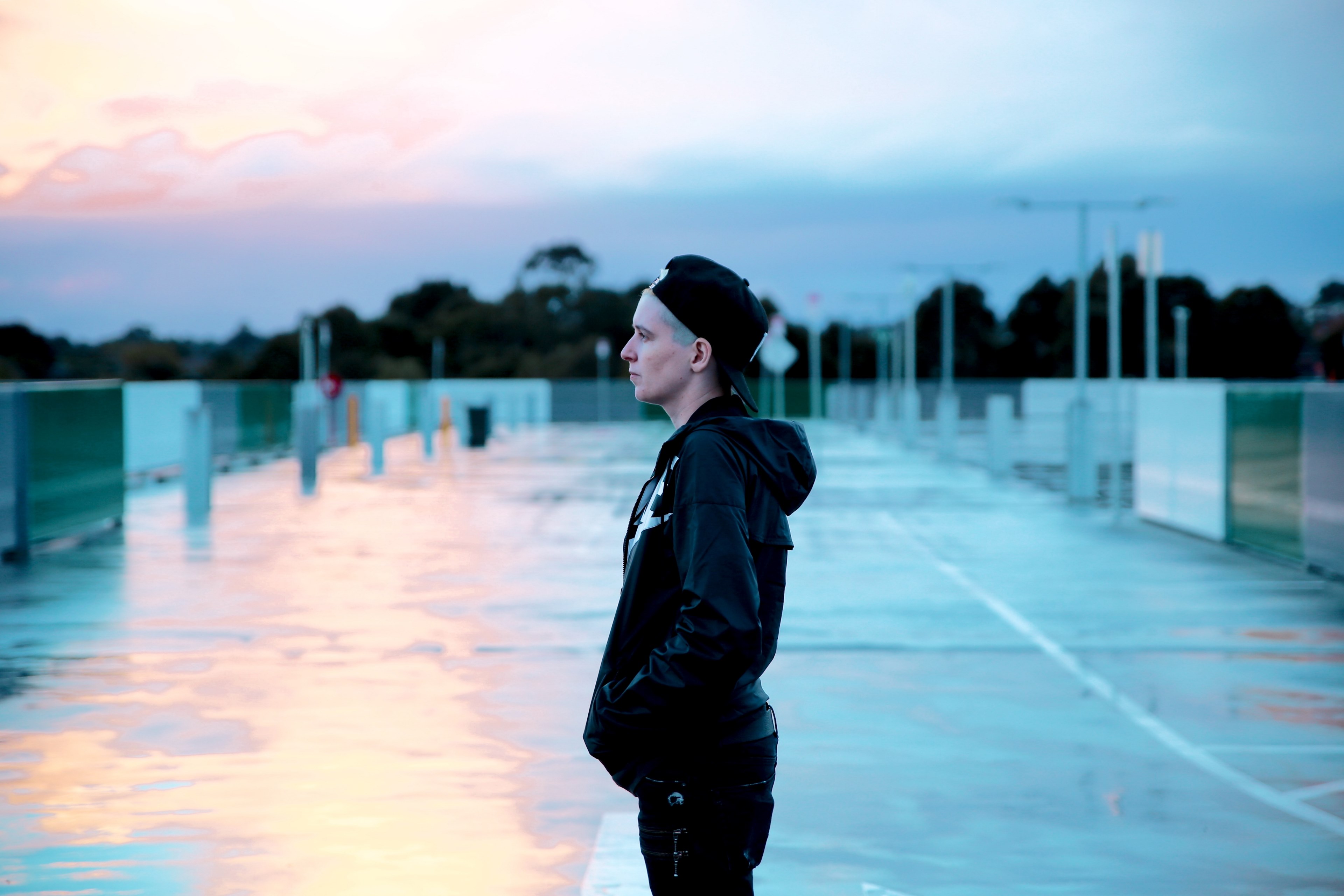 a person in a backwards baseball cap and black clothing stands on sunny pavement, person on sunny pavement 4k, HD Wallpaper