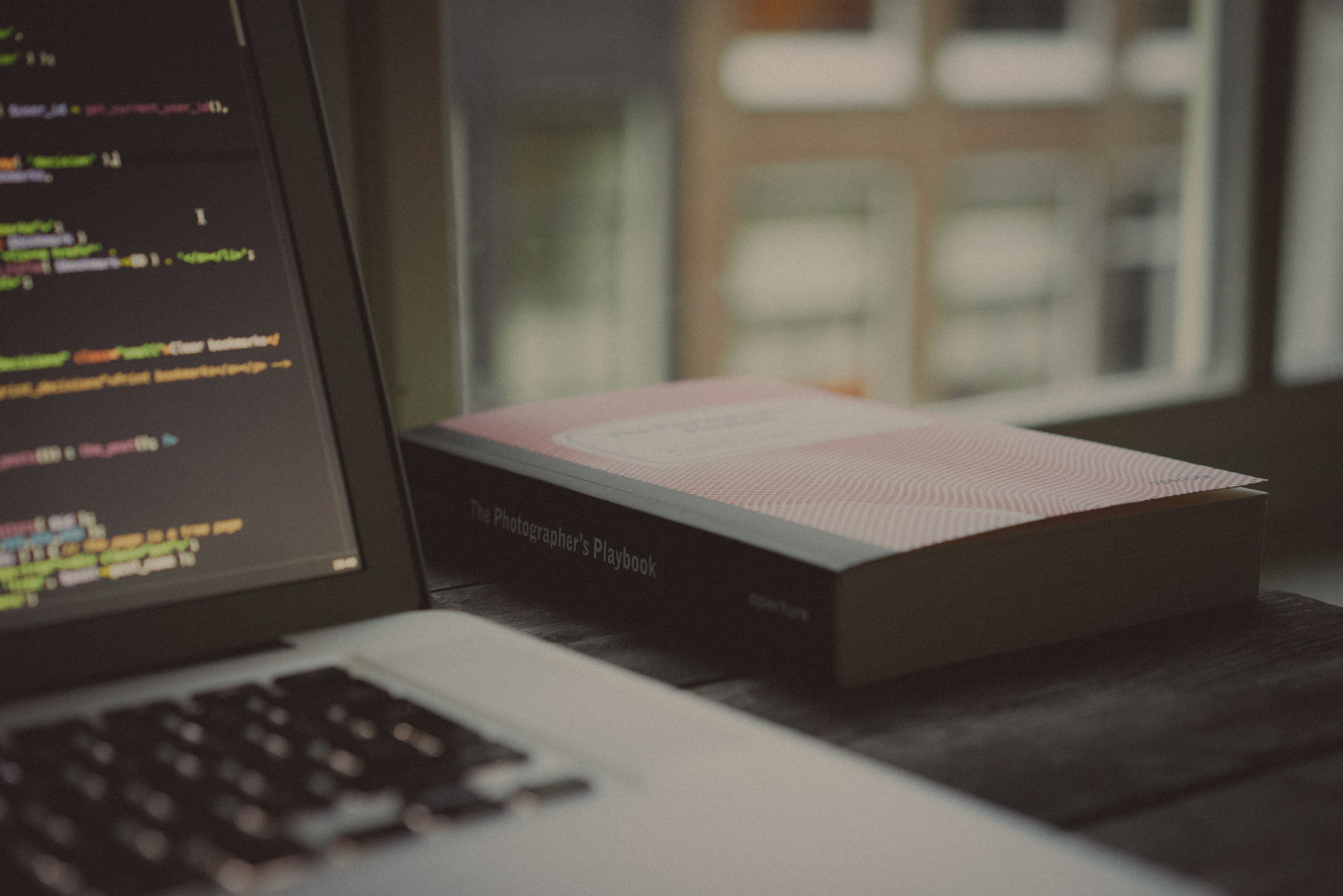 the photographers playbook on a desk next to a laptop with lines of code on its screen, two loves 4k, HD Wallpaper