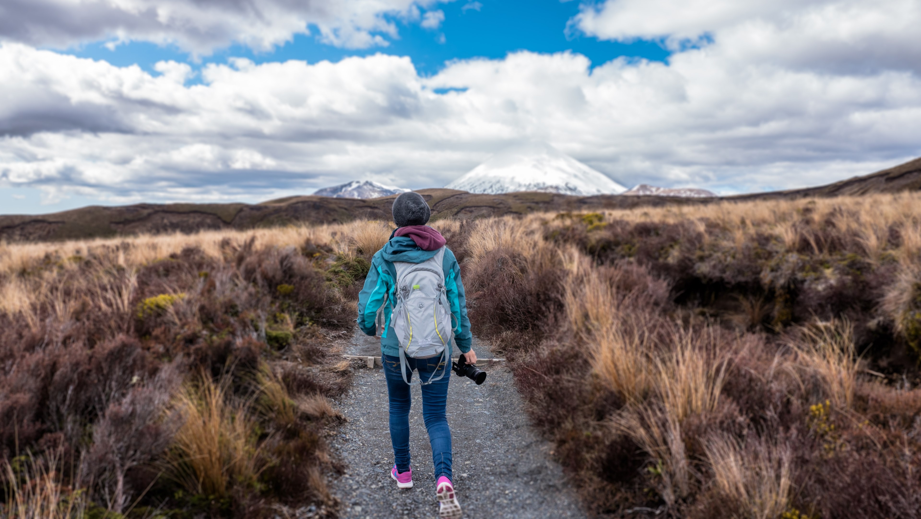 person in jacket with backpack and camera hiking in tongariro national park near snowcapped mountains, trail walk 4k, HD Wallpaper