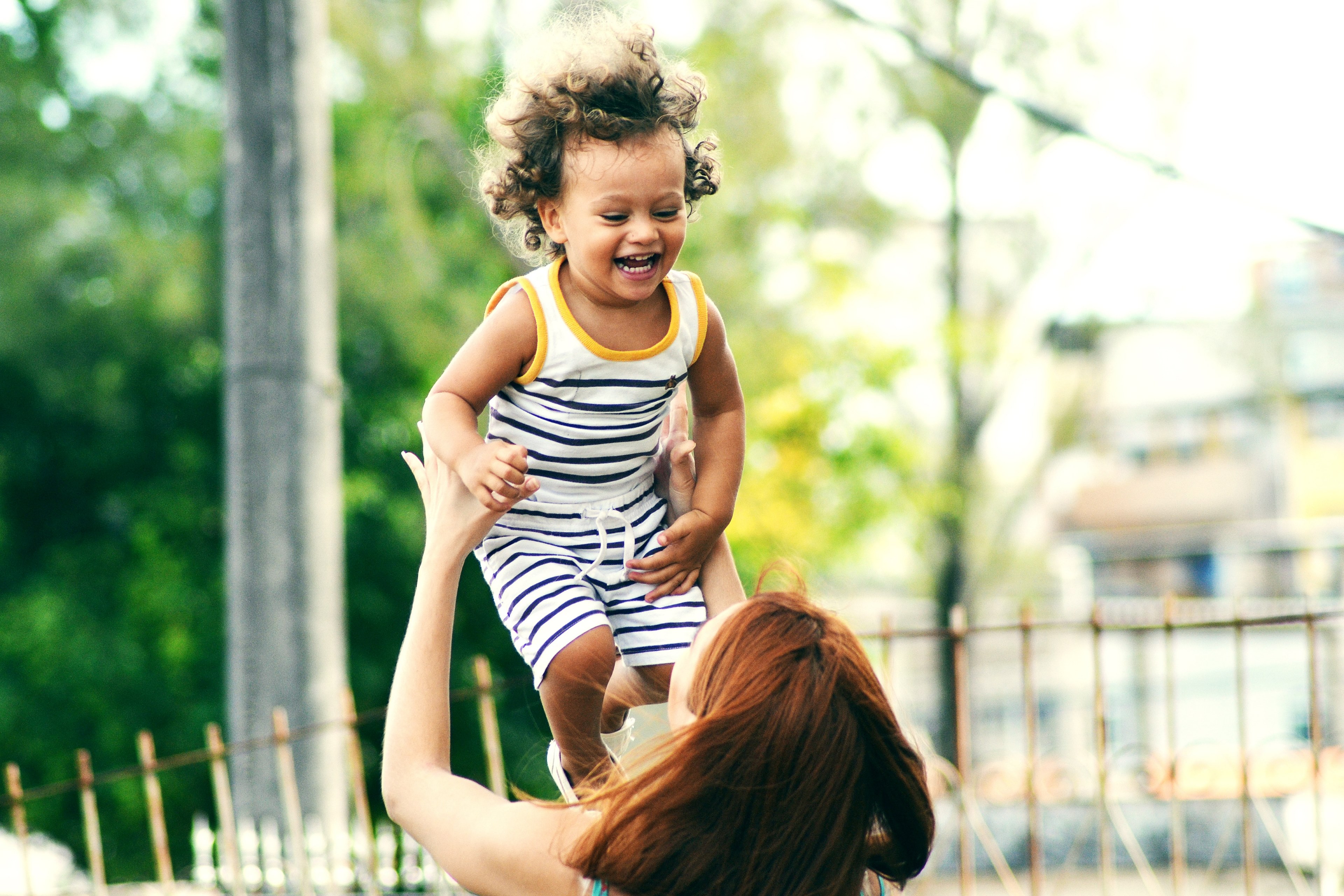 a young girl with curly hair wearing a striped outfit laughing as her brunette mom throws her in the air salvador, air happiness 4k, HD Wallpaper