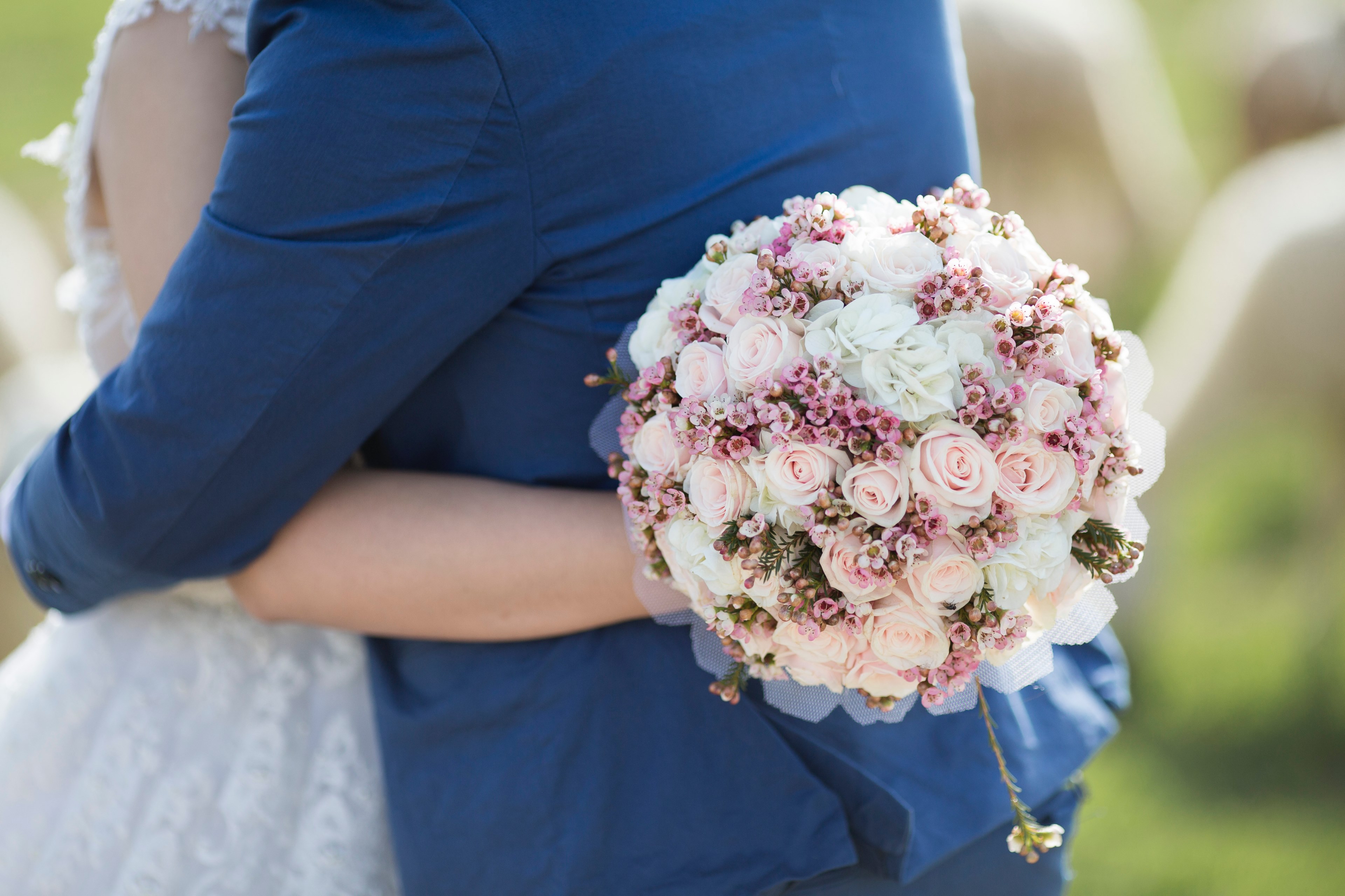 a bride embraces her groom while holding a beautiful floral bouquet behind his back, floral embrace 4k, HD Wallpaper
