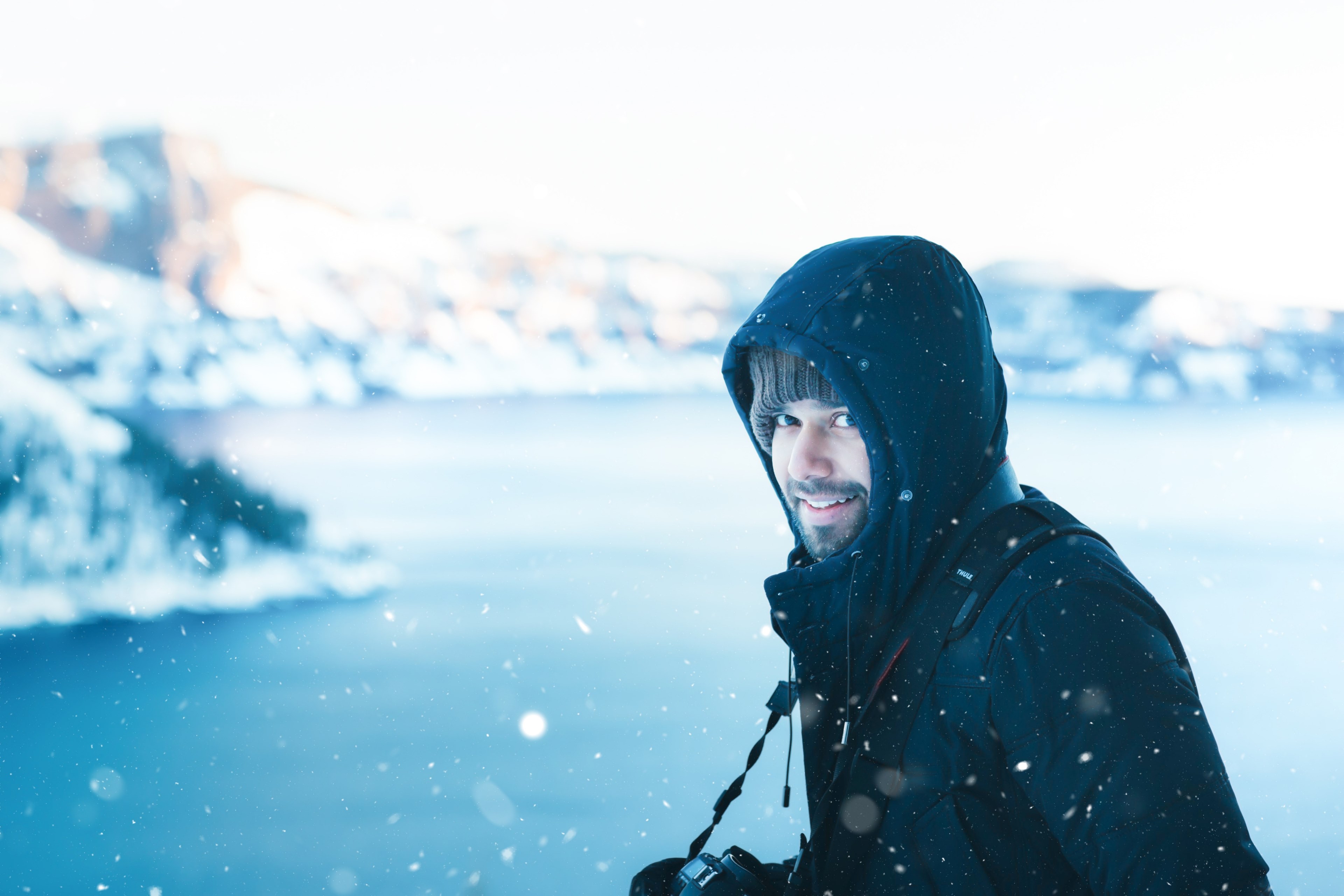 a man smiling at the camera while walking alongside crater lake taken during the winter, snow encounter 4k, HD Wallpaper