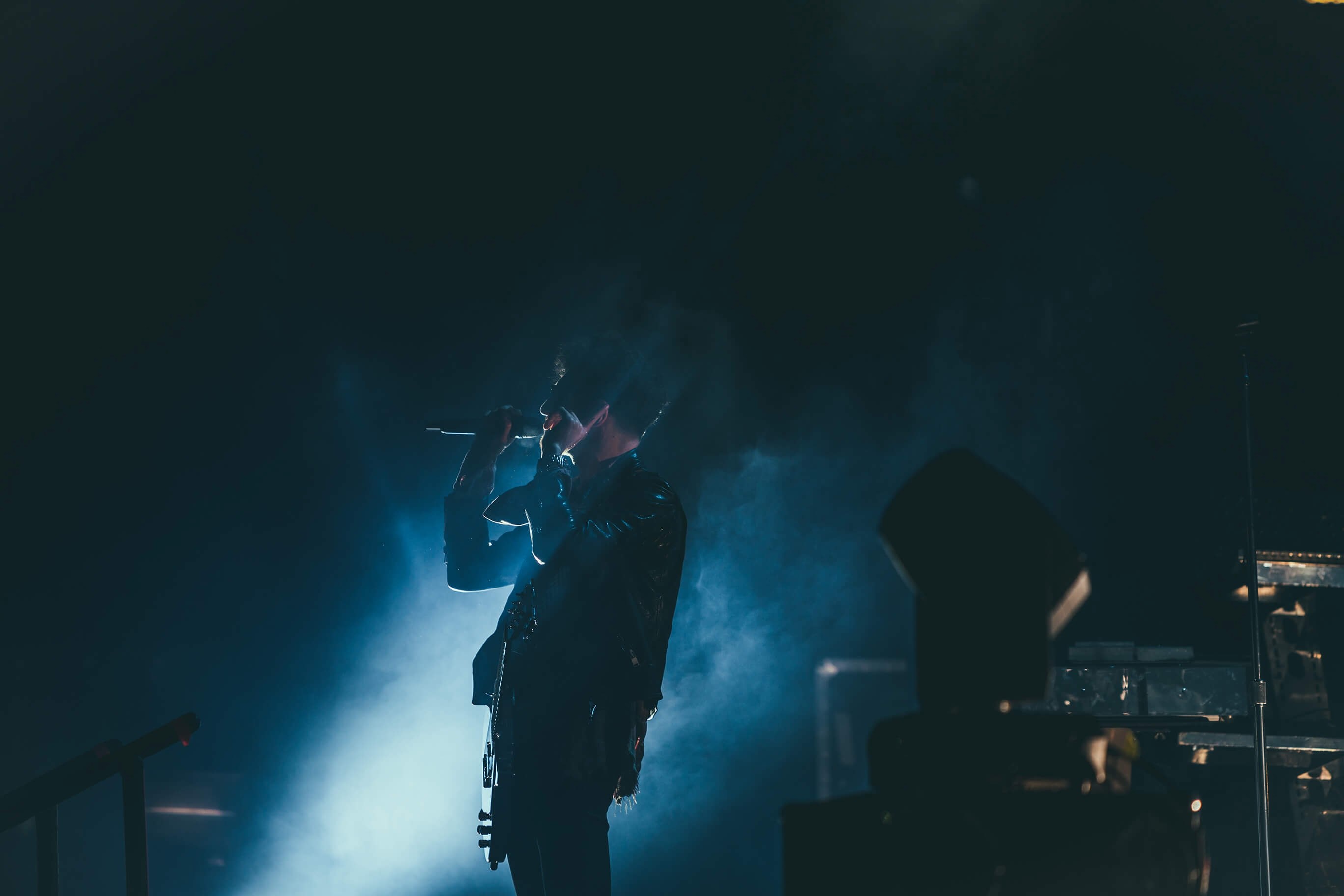 a dim shot of a musician with a microphone on stage engulfed in bluish smoke, rockstar in blue smoke 4k, HD Wallpaper