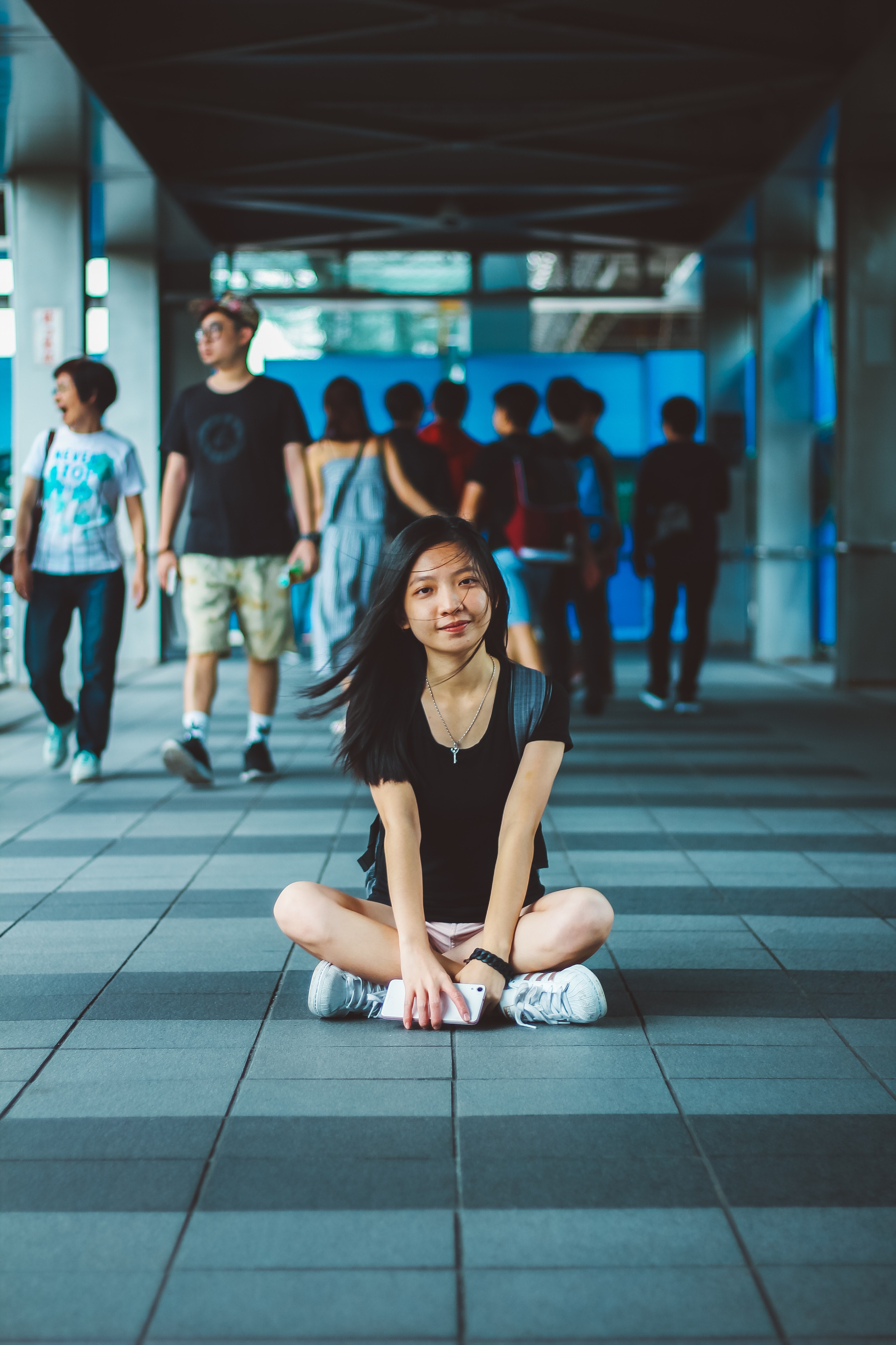 a woman sits on a tiled floor at taipei 101 holding an iphone, hustle bustle 4k, Phone HD Wallpaper