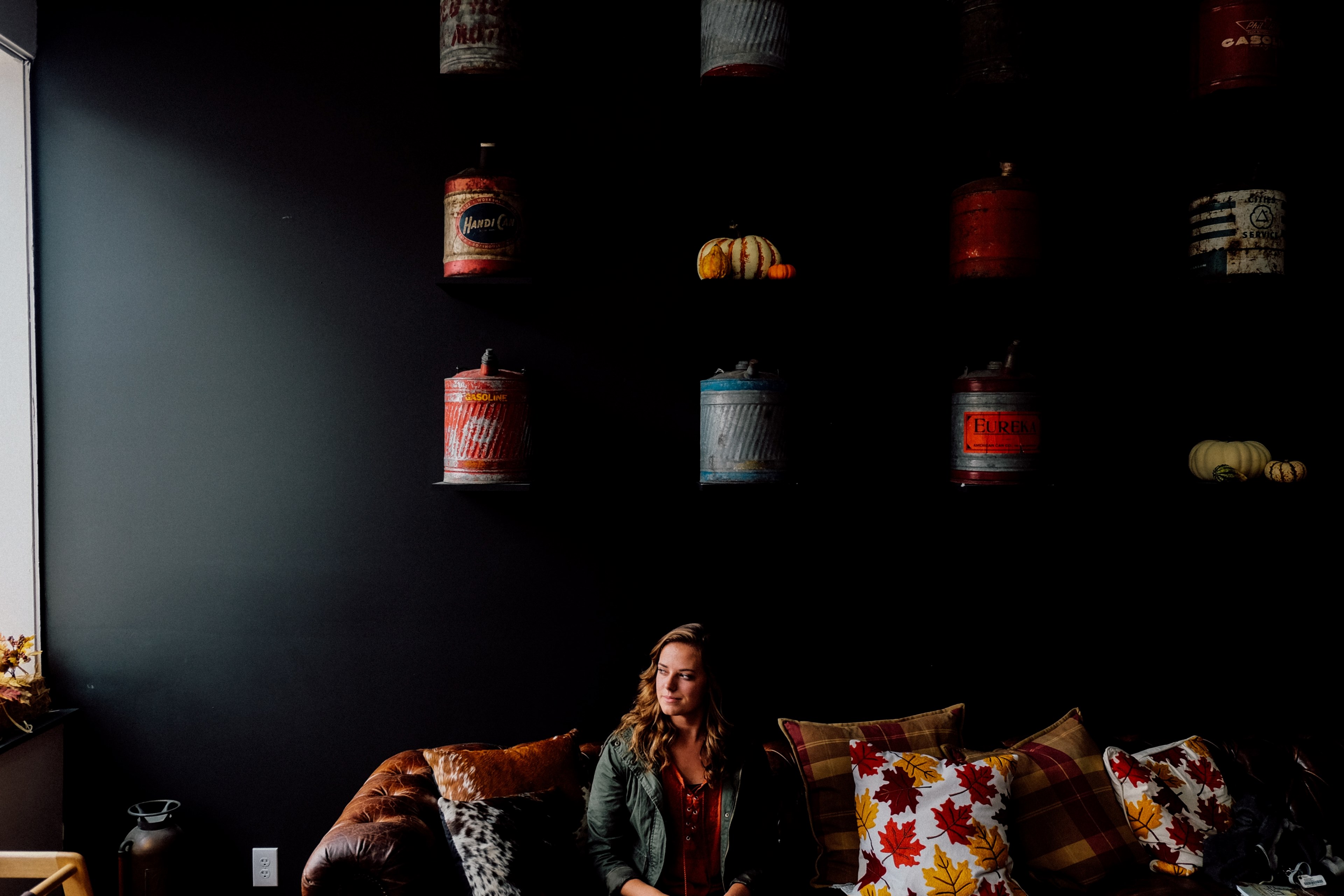 a woman sitting on a couch with cushions covered in leaves at rustbelt coffee, woman among couch cushions 4k, HD Wallpaper