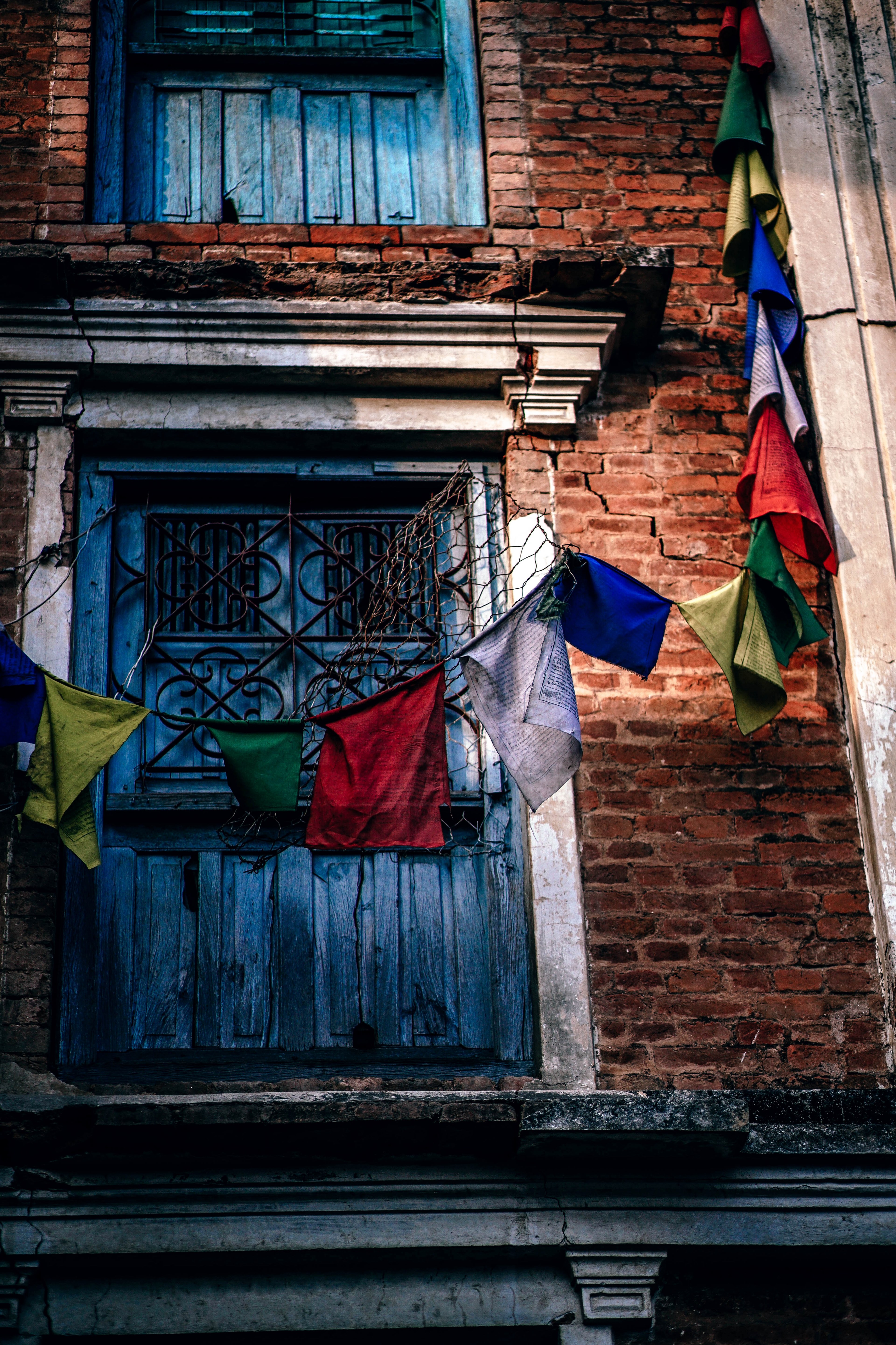 a brick building with blue window shutters and colored flags around it in swayambhu stupa, vintage prayer flags 4k, Phone HD Wallpaper