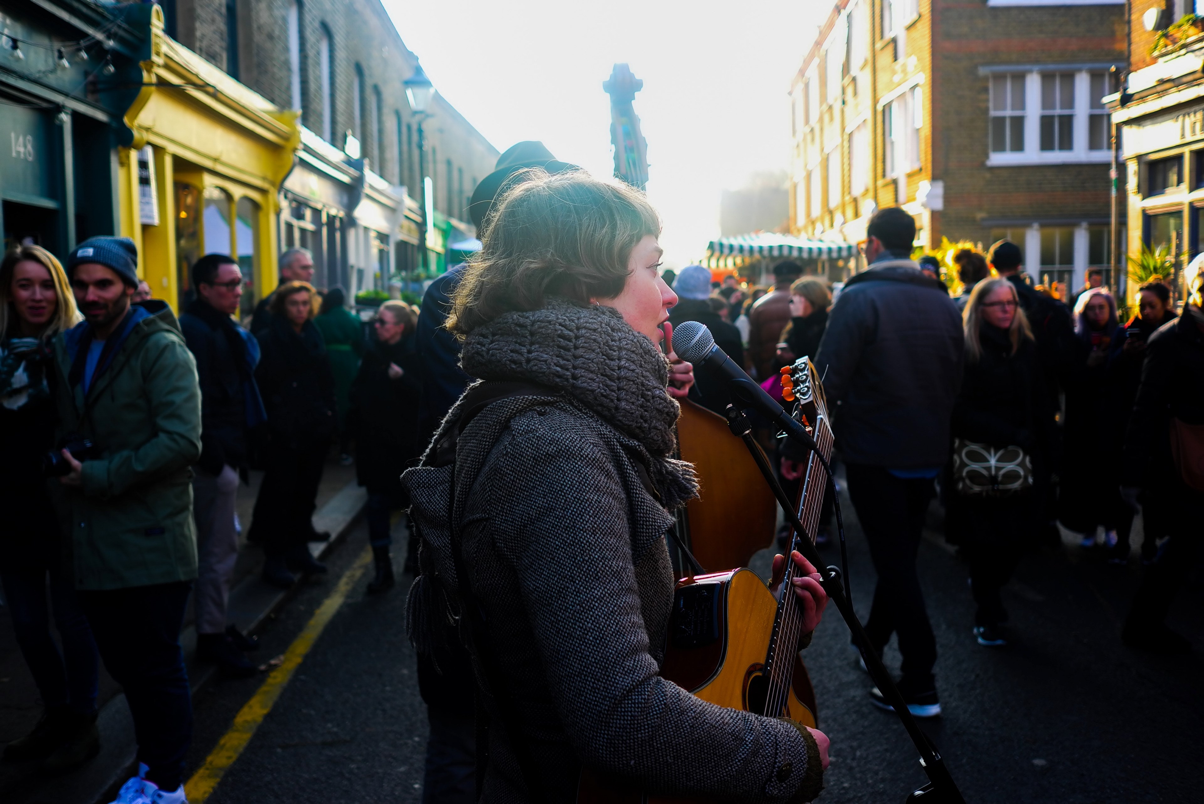 a woman playing acoustic guitar and singing into the microphone on a crowded street, and sing 4k, HD Wallpaper