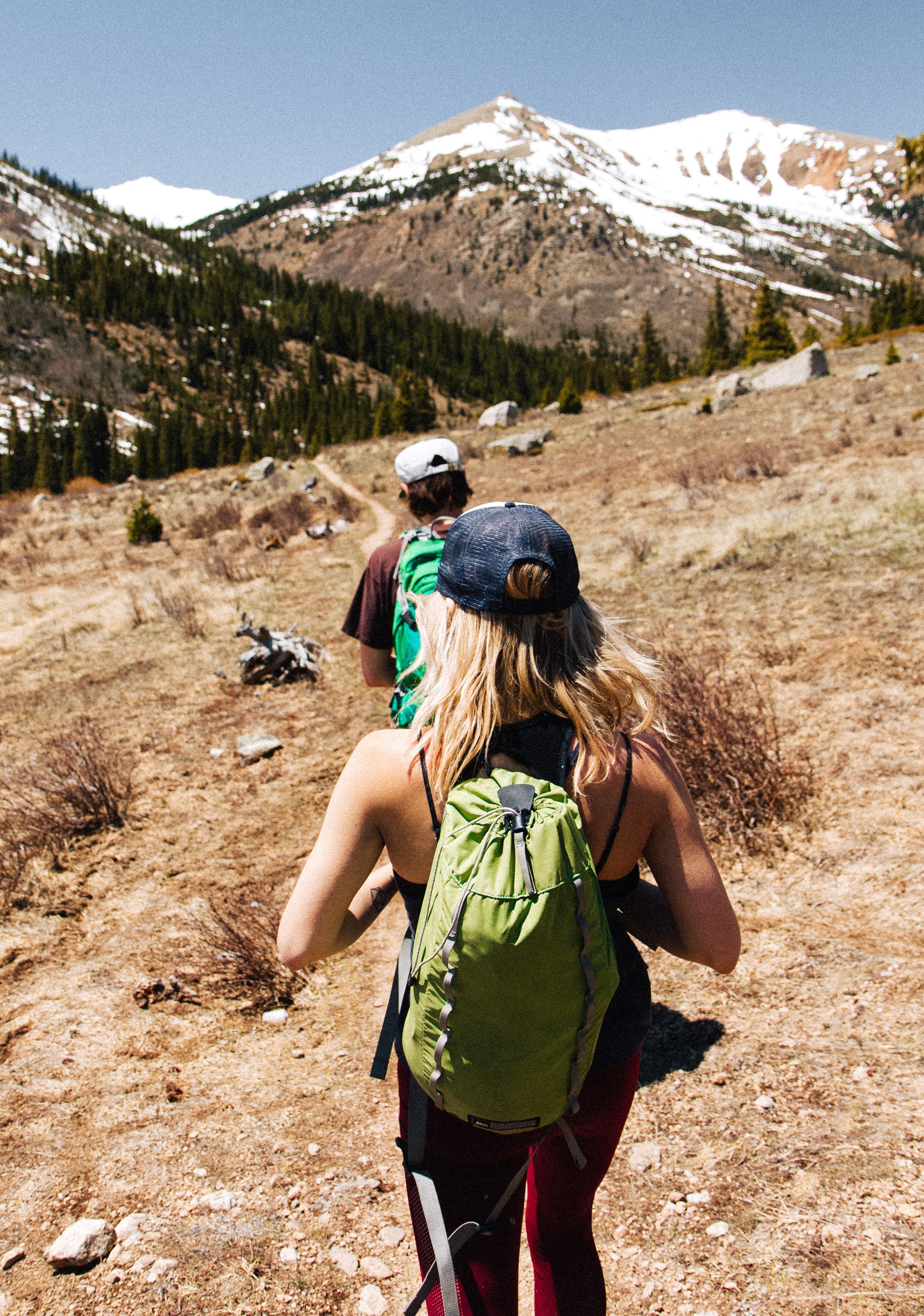hikers walk through a hot deserted field to get to snowy mountains, friends hiking 4k, Phone HD Wallpaper