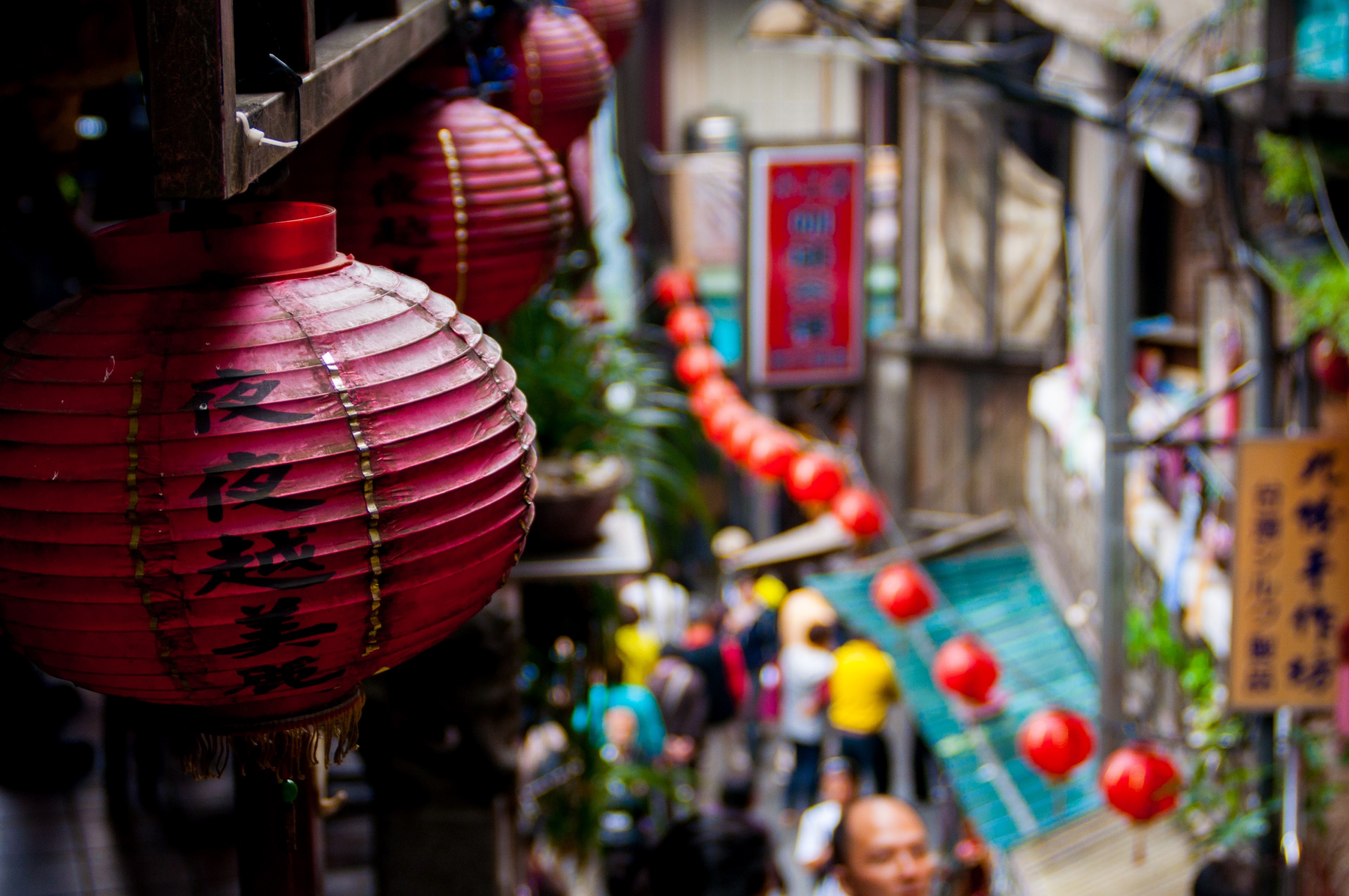 the macro view of chinese lanterns placed on walls and a blurry view of people walking in a market road in jiufen old street, _chinese lanterns in market 4k, HD Wallpaper