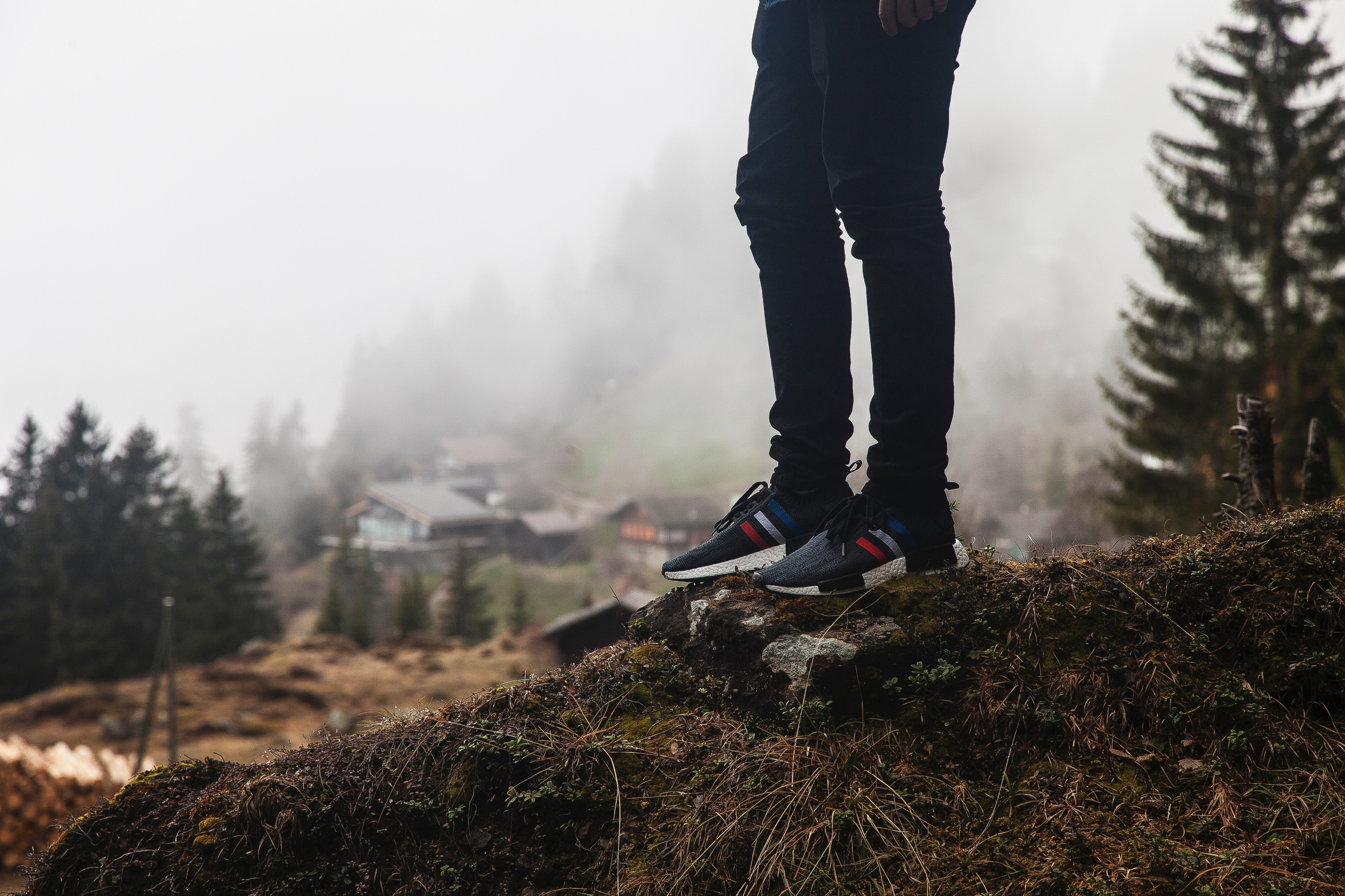 person wearing jeans and casual sneakers atop a hill near cottages, hikers legs and shoes 4k, HD Wallpaper