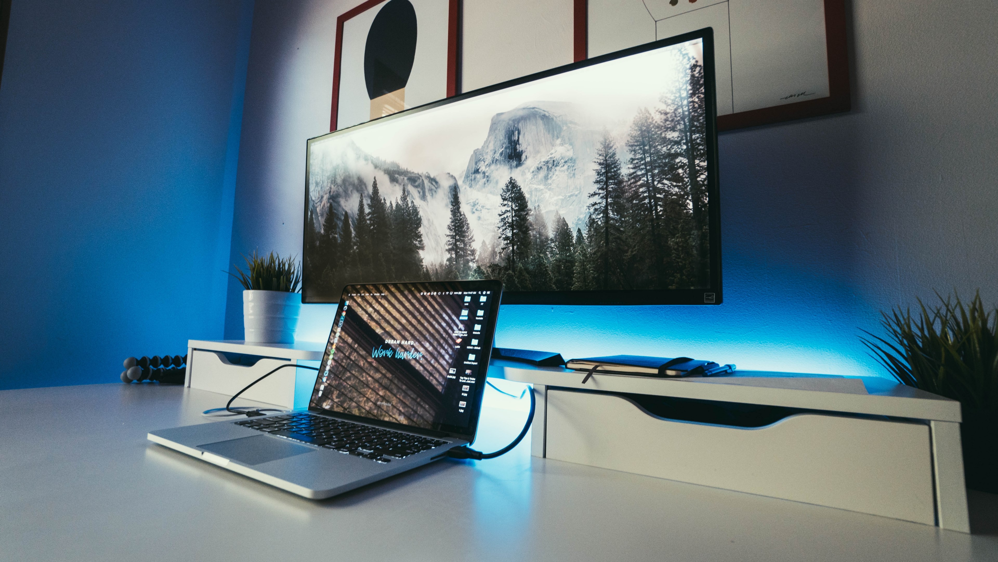 large computer monitor displaying mountains on desk behind macbook laptop in dark room, follow my instagram wwwinstagram_comnateggrant 4k, HD Wallpaper