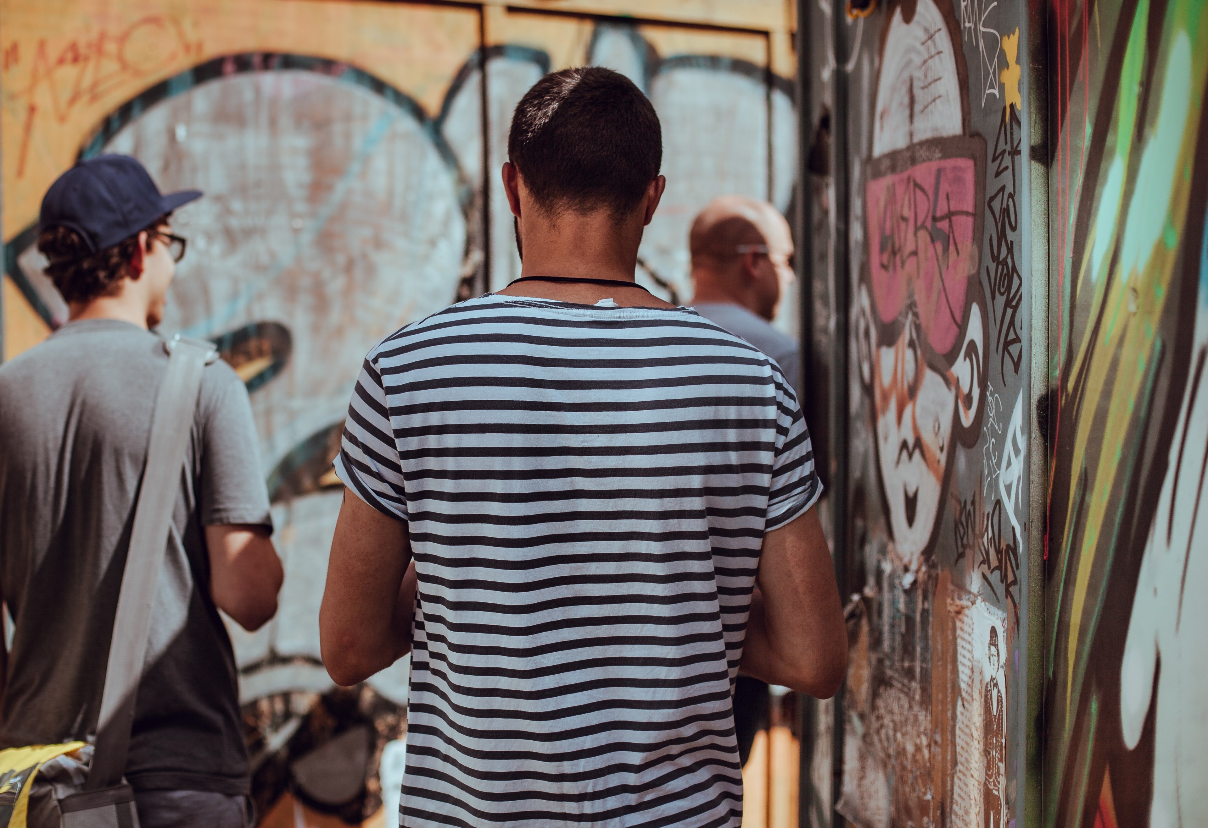 a man facing away in a striped t shirt aside brightly colored graffitied walls, city strollers 4k, HD Wallpaper