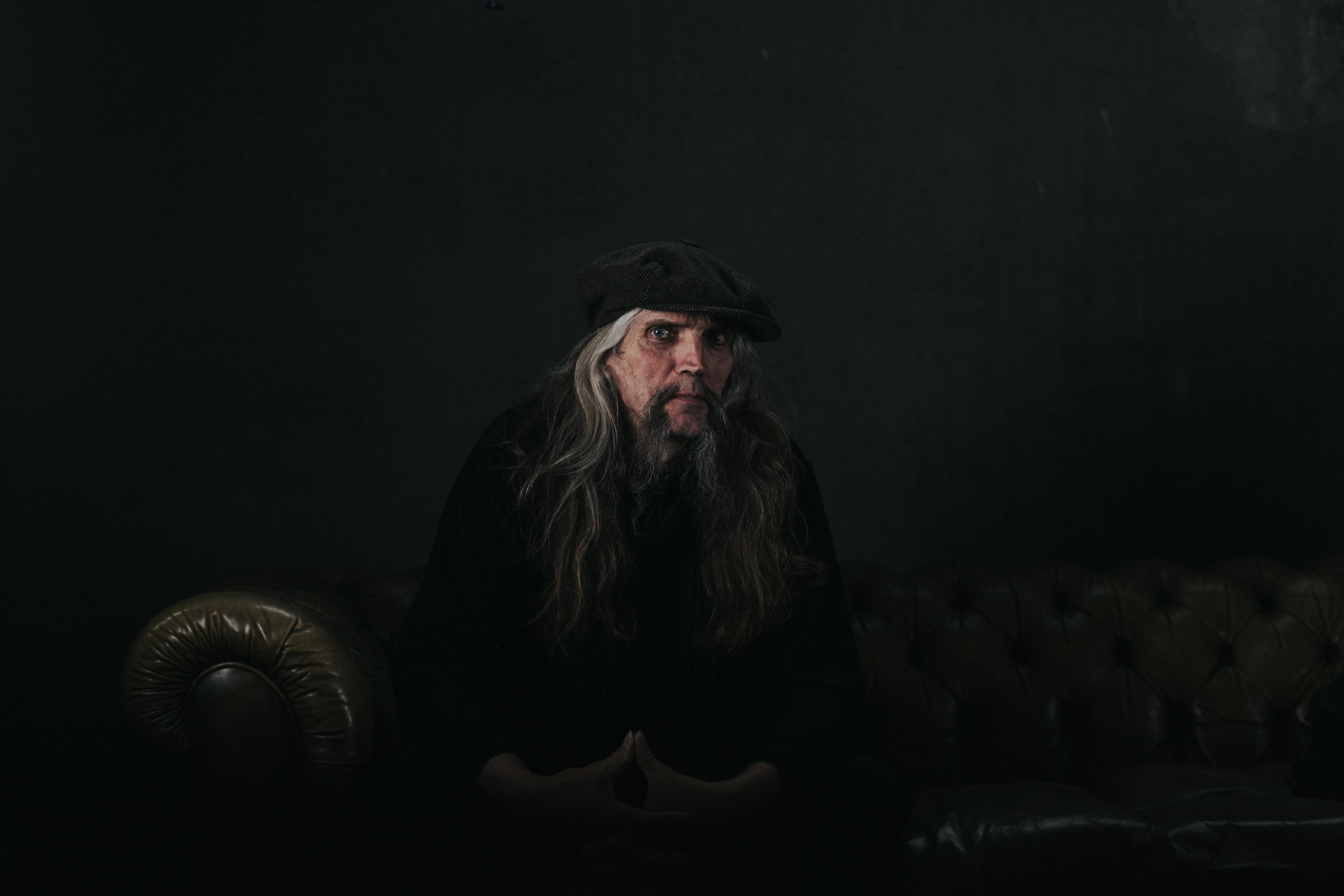 a man with long gray hair sits on a couch against a black background, man with long gray hair 4k, HD Wallpaper