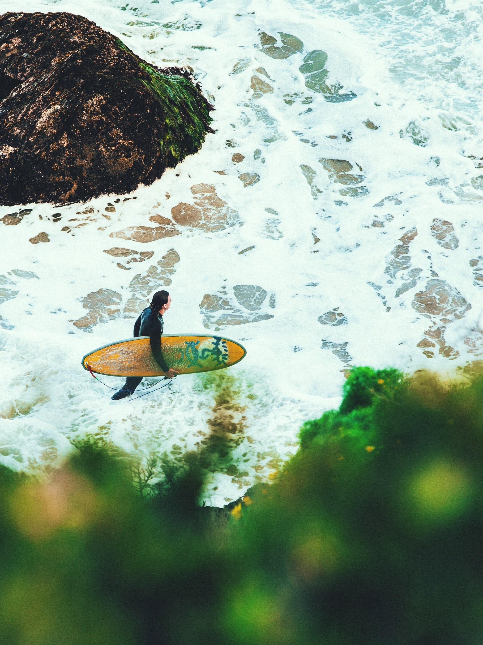 a male surfer in a wetsuit carrying a board into the foaming sea surrounded by rock formations at point dume, surfer surf and rocks 4k, Phone HD Wallpaper