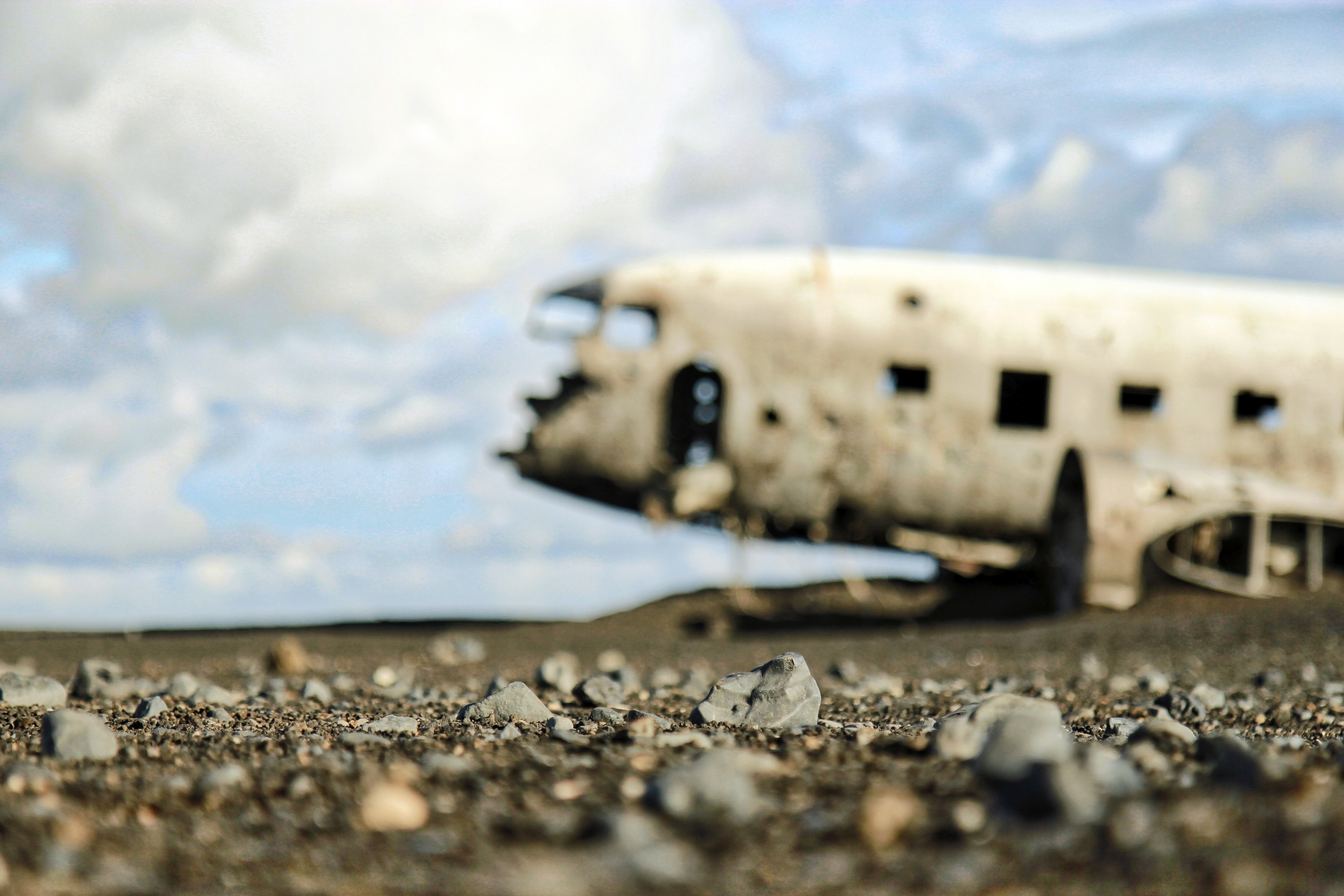 macro view of pebbles with blurry plane wreckage and cloudy sky in the background, pebbles and plane wreck 4k, HD Wallpaper