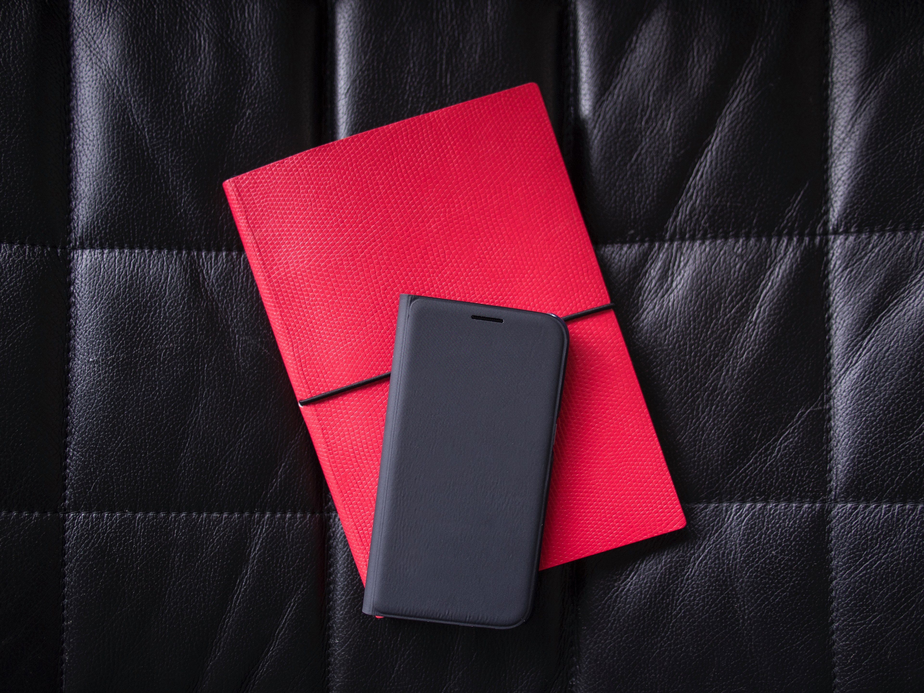 a phone in a black case on a red notebook laid out on a leather surface, black and red tech 4k, HD Wallpaper