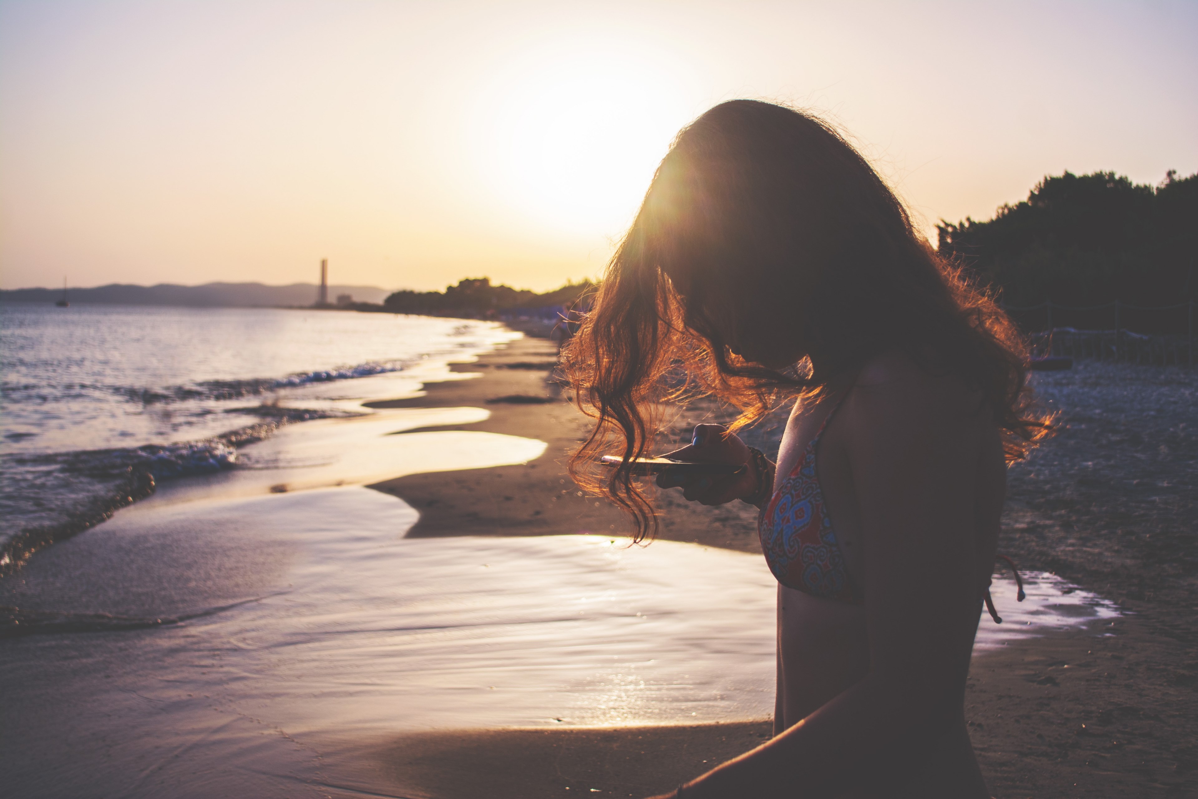 woman in swimsuit typing on the smartphone on the sand beach at sunset in oasi sosta camper, woman with smartphone on beach 4k, HD Wallpaper