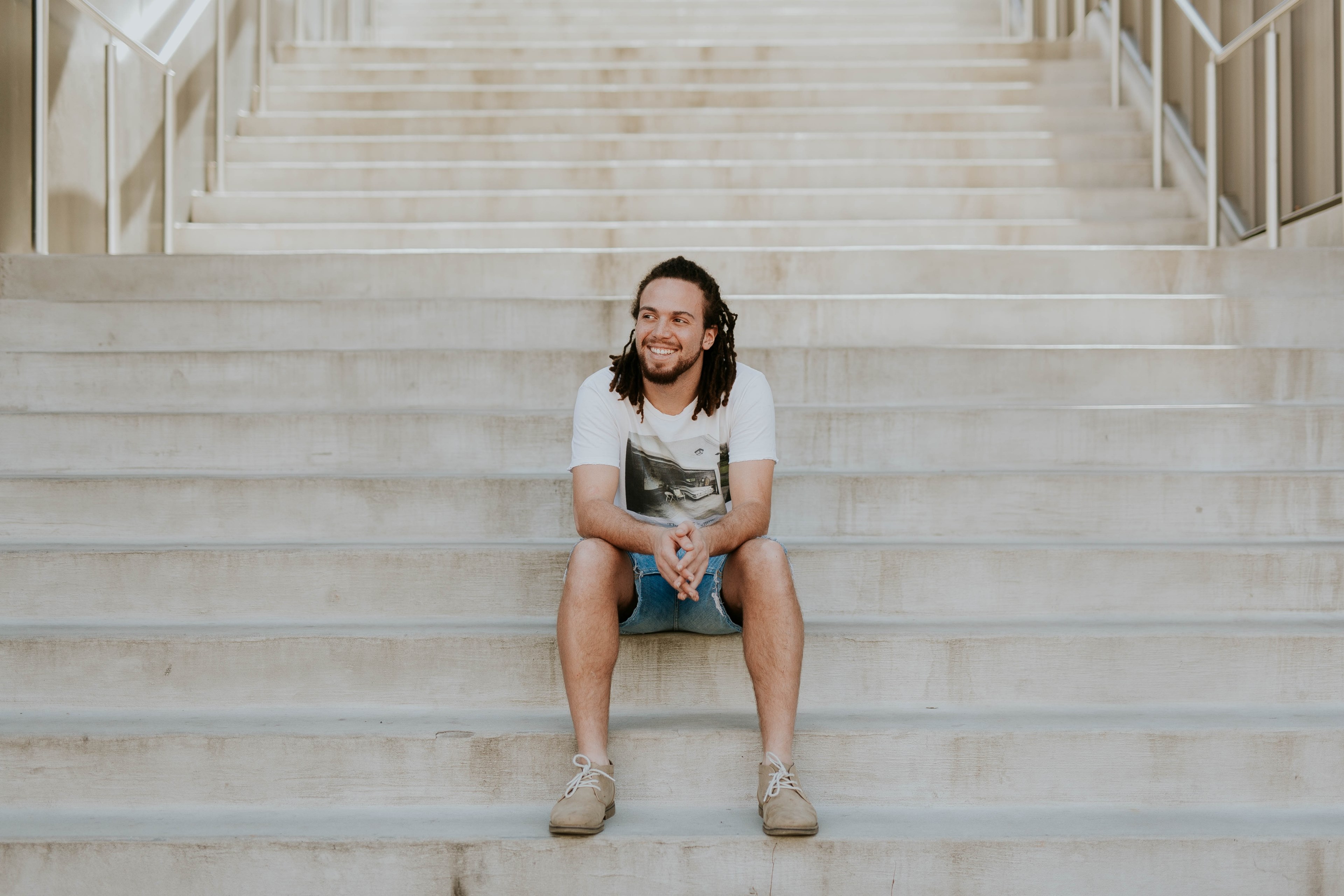 a man with dreadlocks smiles while sitting on steps at the university of arkansas, man smiling on steps 4k, HD Wallpaper