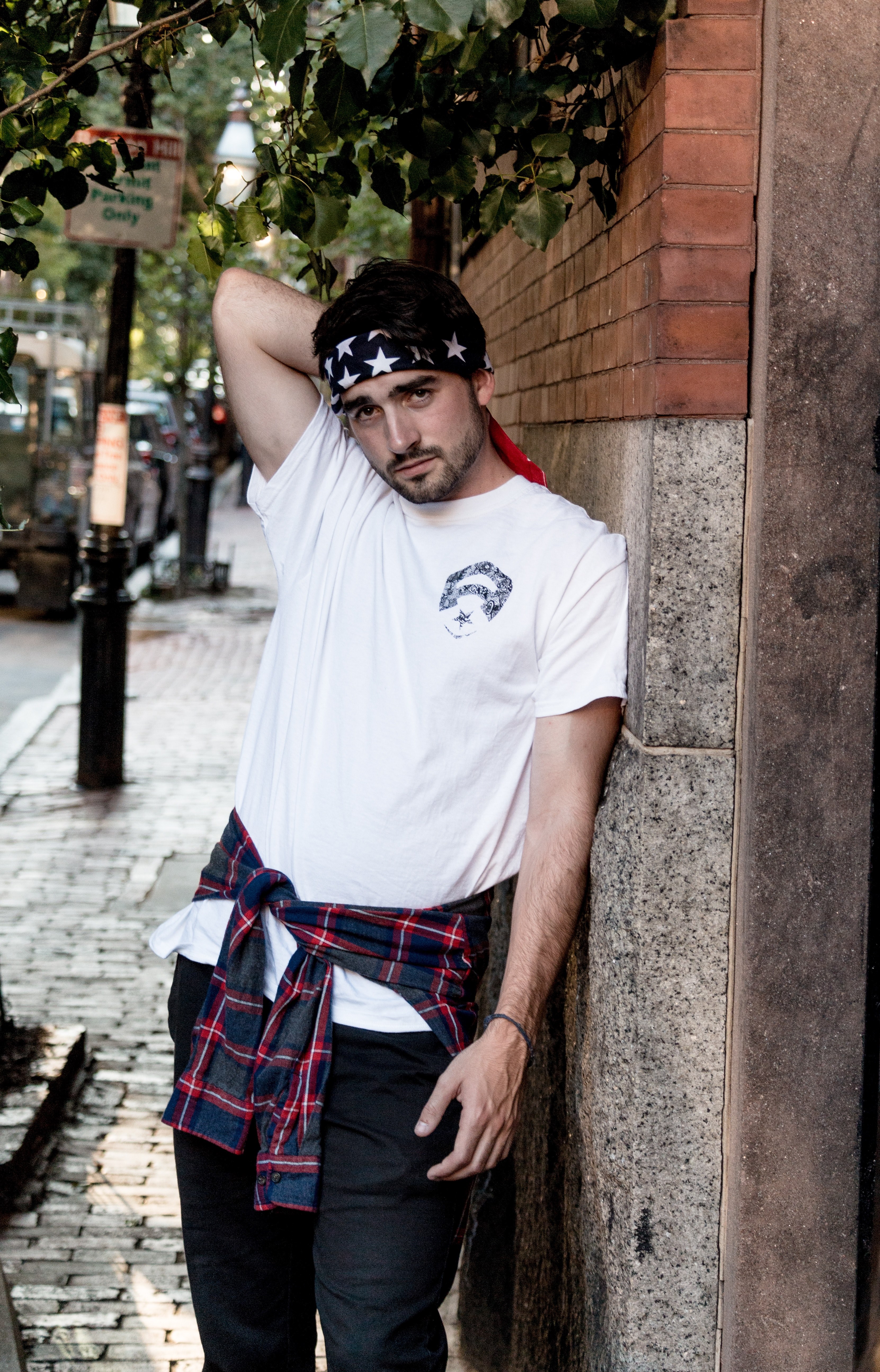 a man wearing an american flag bandana white shirt and flannel tied around his waist leaning against a brick wall in boston, boston street portrait 4k, Phone HD Wallpaper