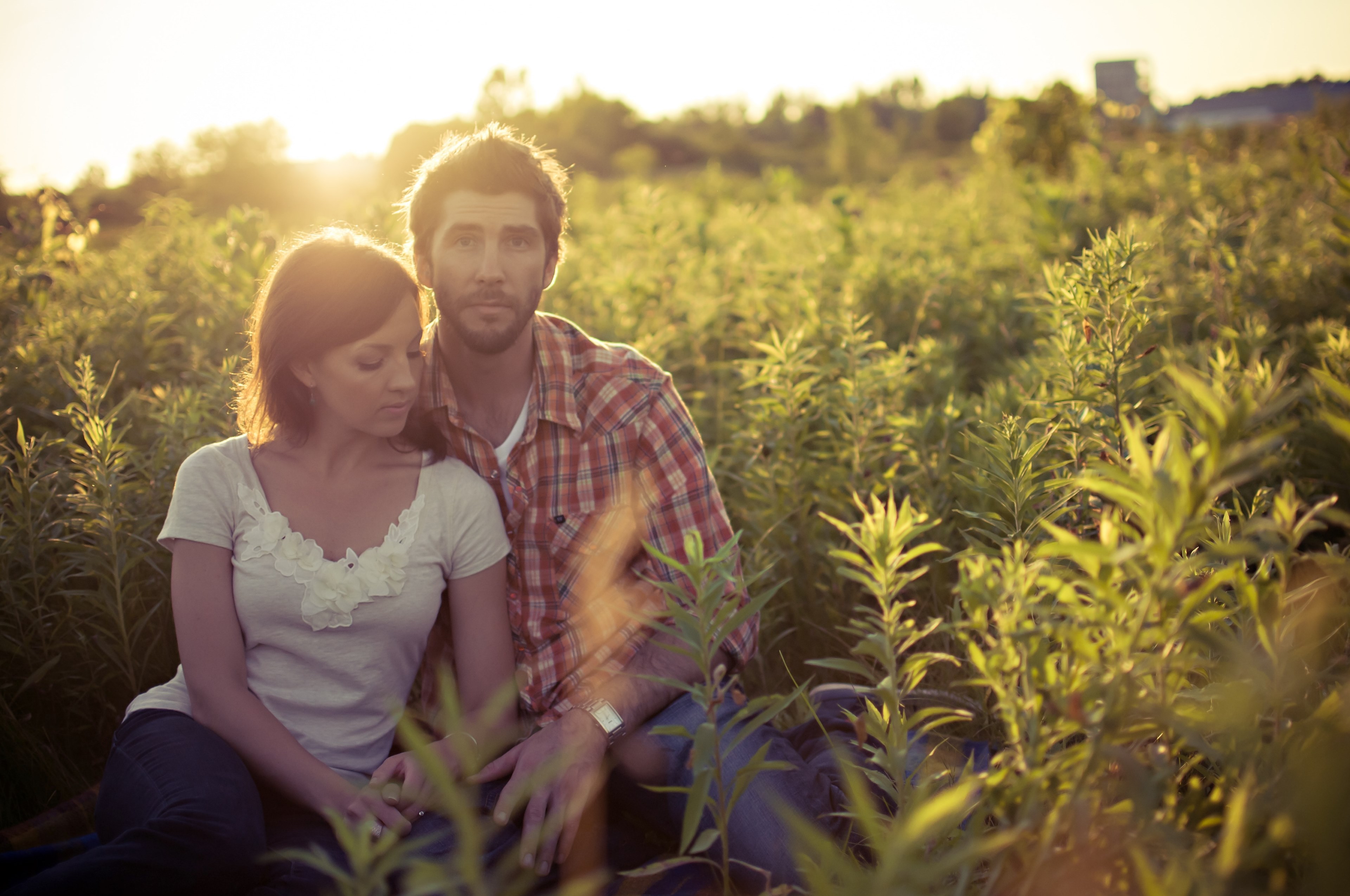 a casually dressed woman leans against a man in a sunny tall green field in london, love story 4k, HD Wallpaper