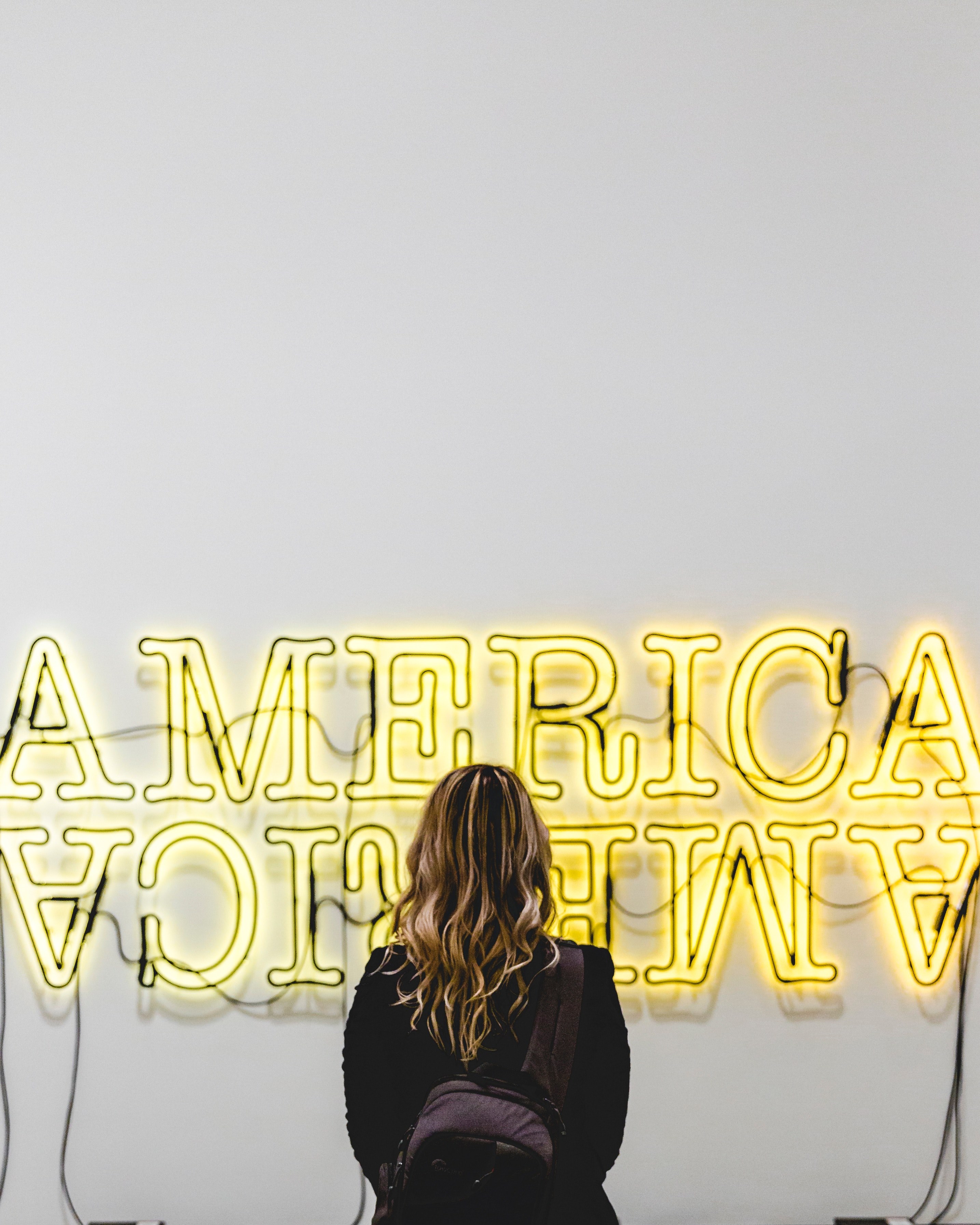 a long haired woman stares at a neon sign at the broad a museum in los angeles california, neon yellow america lights 4k, Phone HD Wallpaper