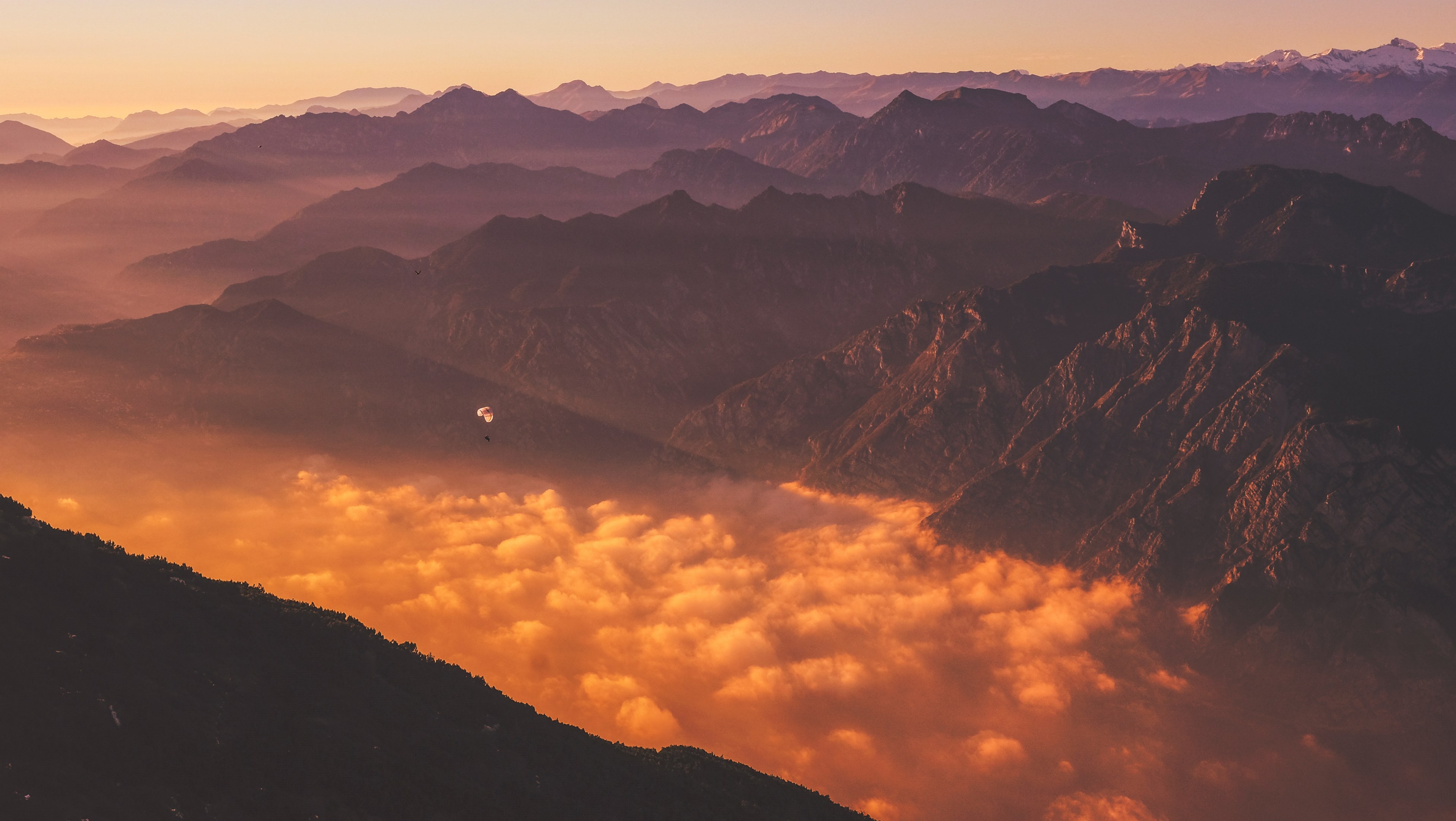 a paraglider over clouds obscuring the bottom of a mountain valley during sunset, orange mountain clouds 4k, HD Wallpaper