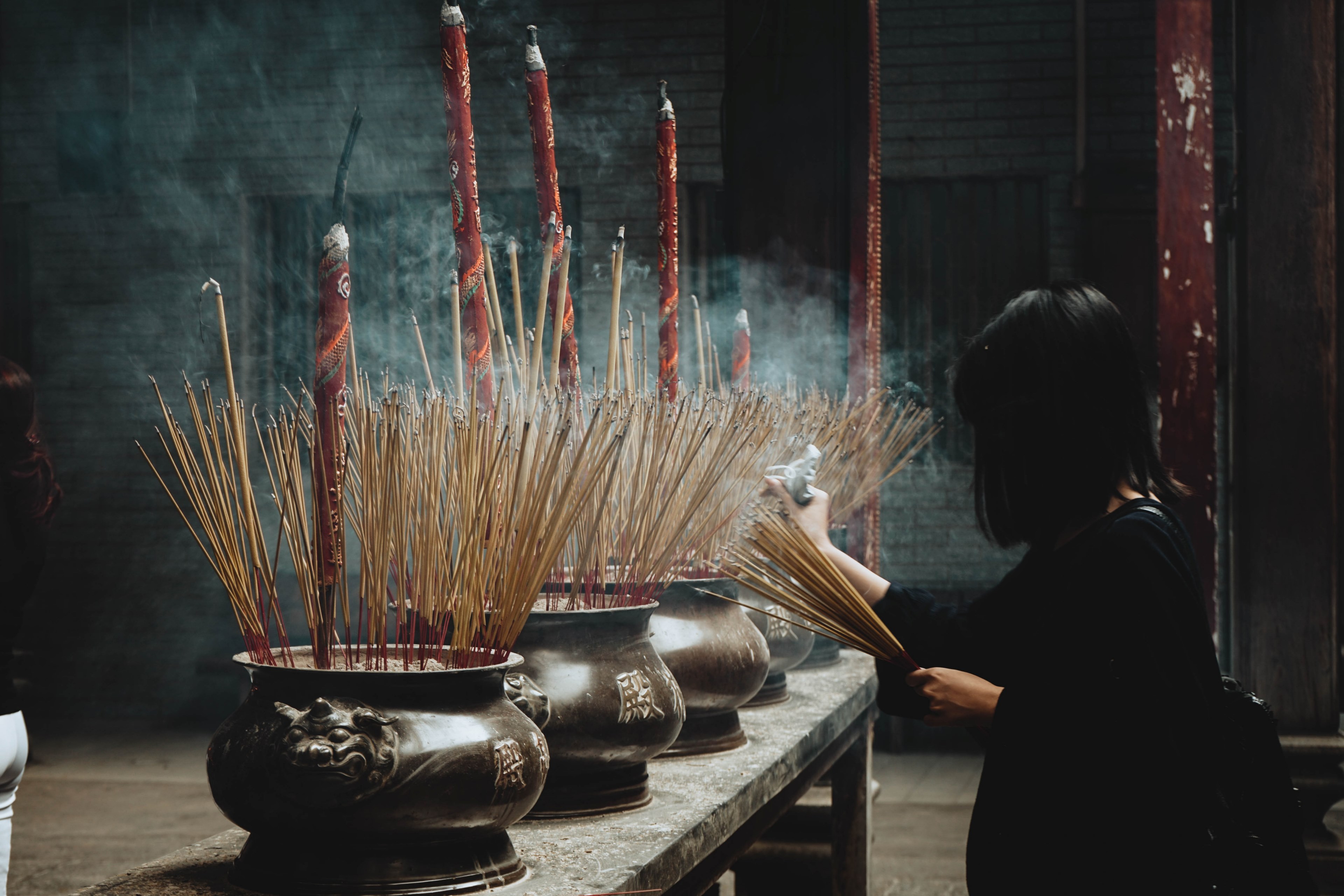 a woman places joss sticks in urns with joss sticks of various sizes in the temple, _in holy smoke 4k, HD Wallpaper
