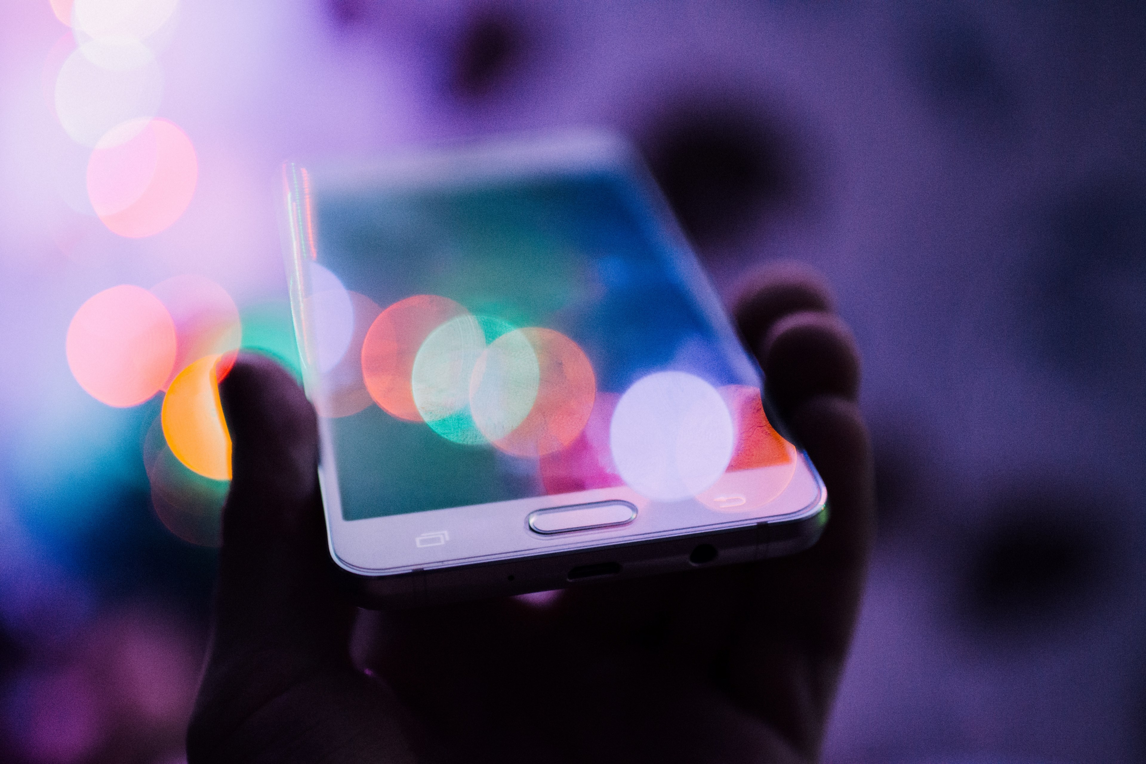 a person holding up a smartphone in their hand with colorful bokeh circles over its screen, cellphone 4k, HD Wallpaper