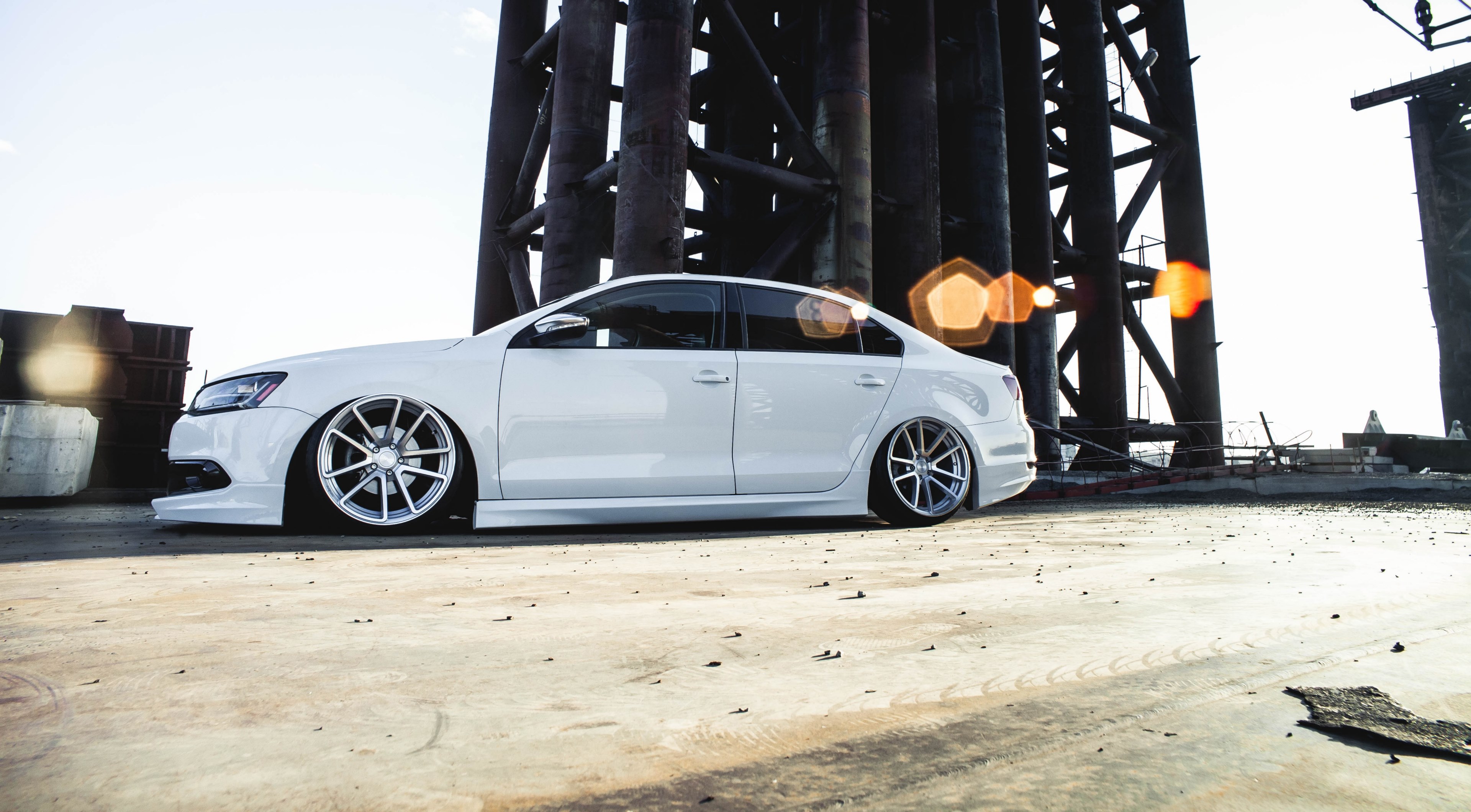 a white sports car is parked next to a steel structure with lens flare effect, _volkswagen jetta 4k, HD Wallpaper