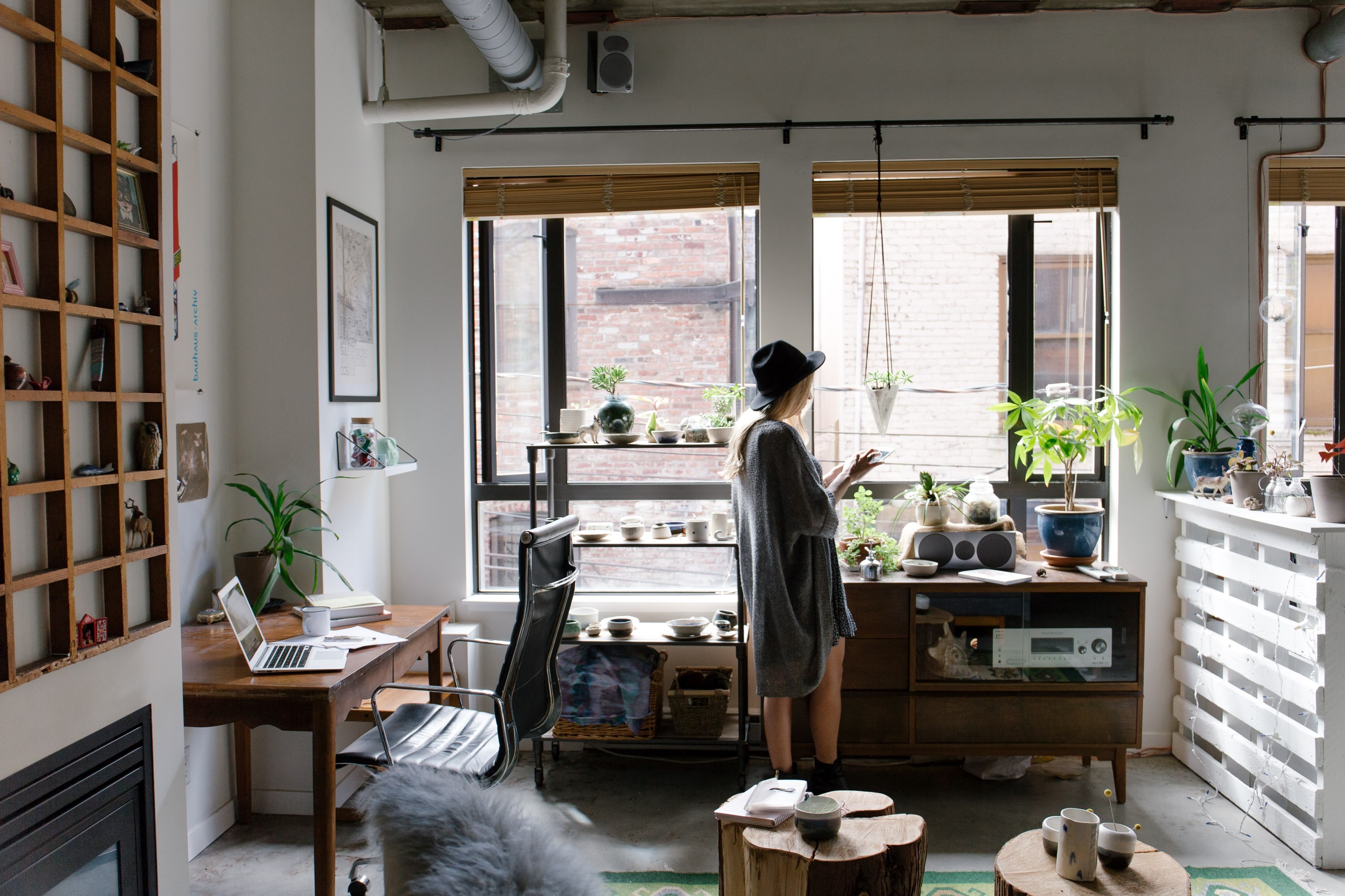 a woman in a hat standing near the window in a bohemian apartment, woman in an artistic room 4k, HD Wallpaper