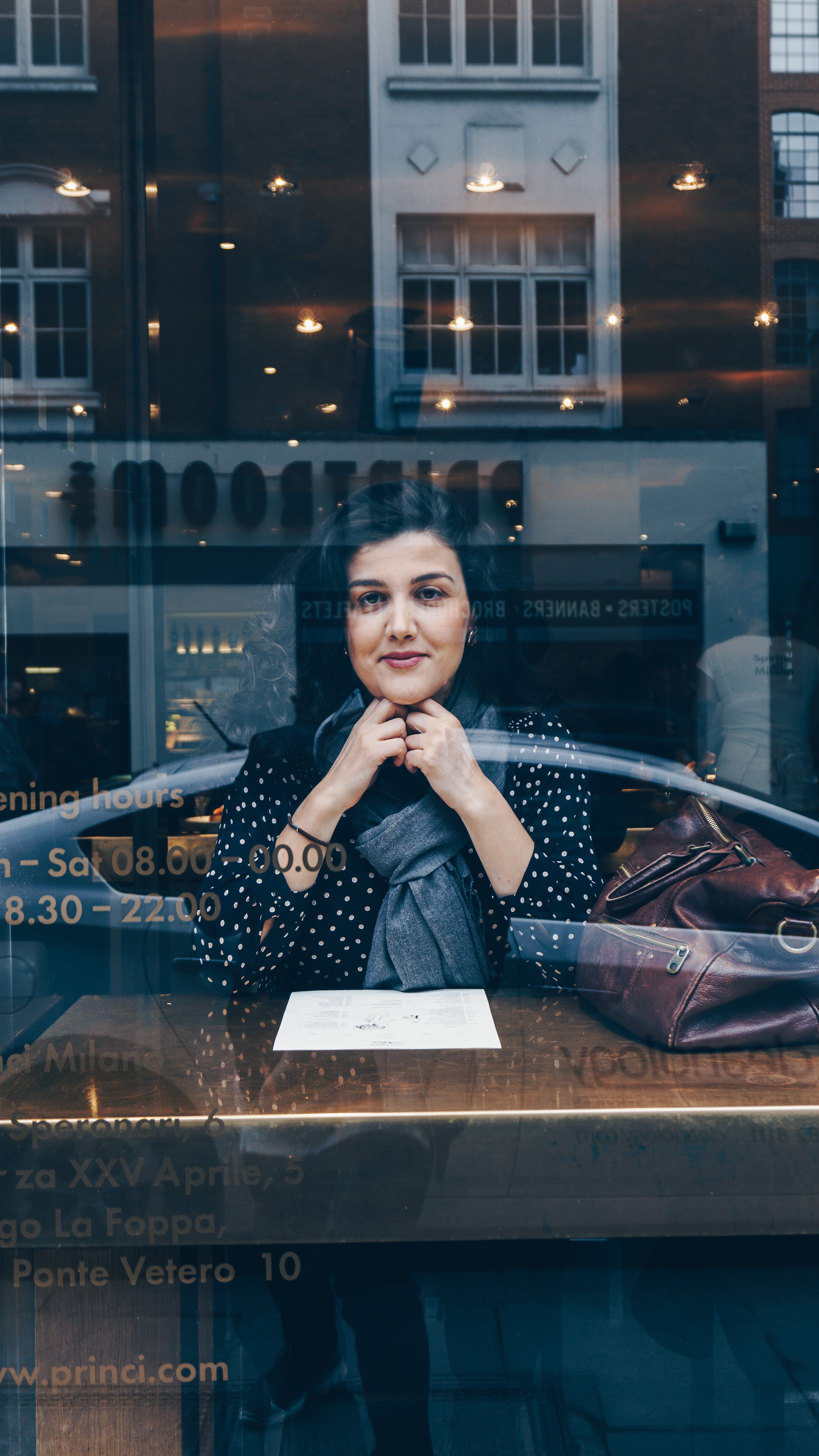 a woman leaning on her arms looks through a cafe window that reflects a city scene, woman through a cafe window 4k, Phone HD Wallpaper