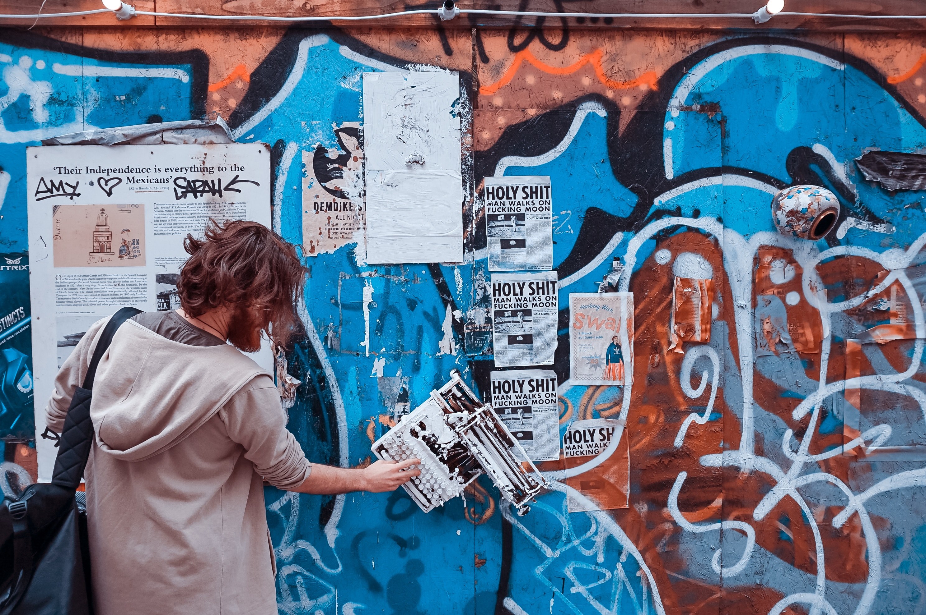 a man putting up posters over a wall covered in graffiti, _typewriting wall 4k, HD Wallpaper
