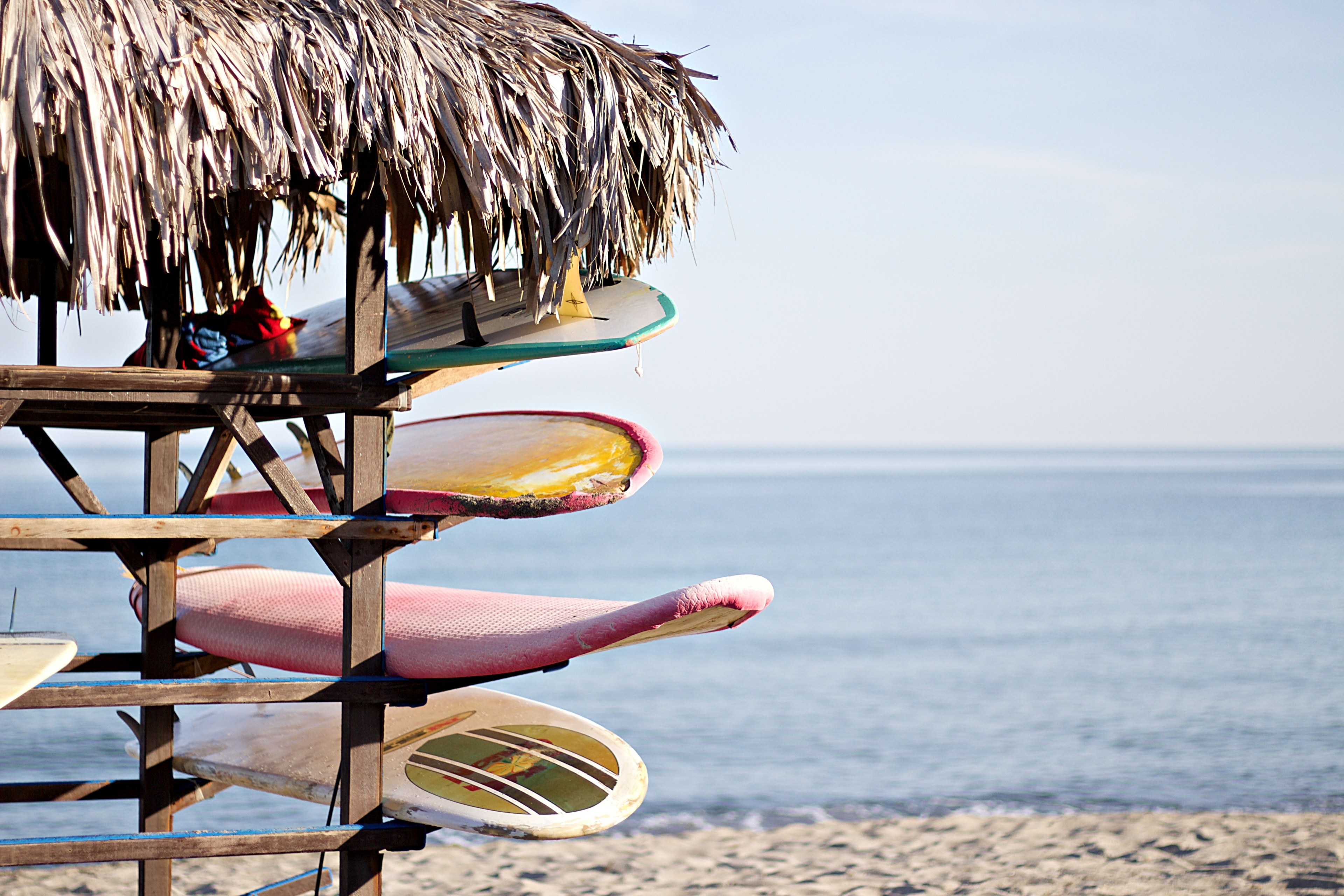 four surfboards on racks under a thatch roof, awaiting surf 4k, HD Wallpaper