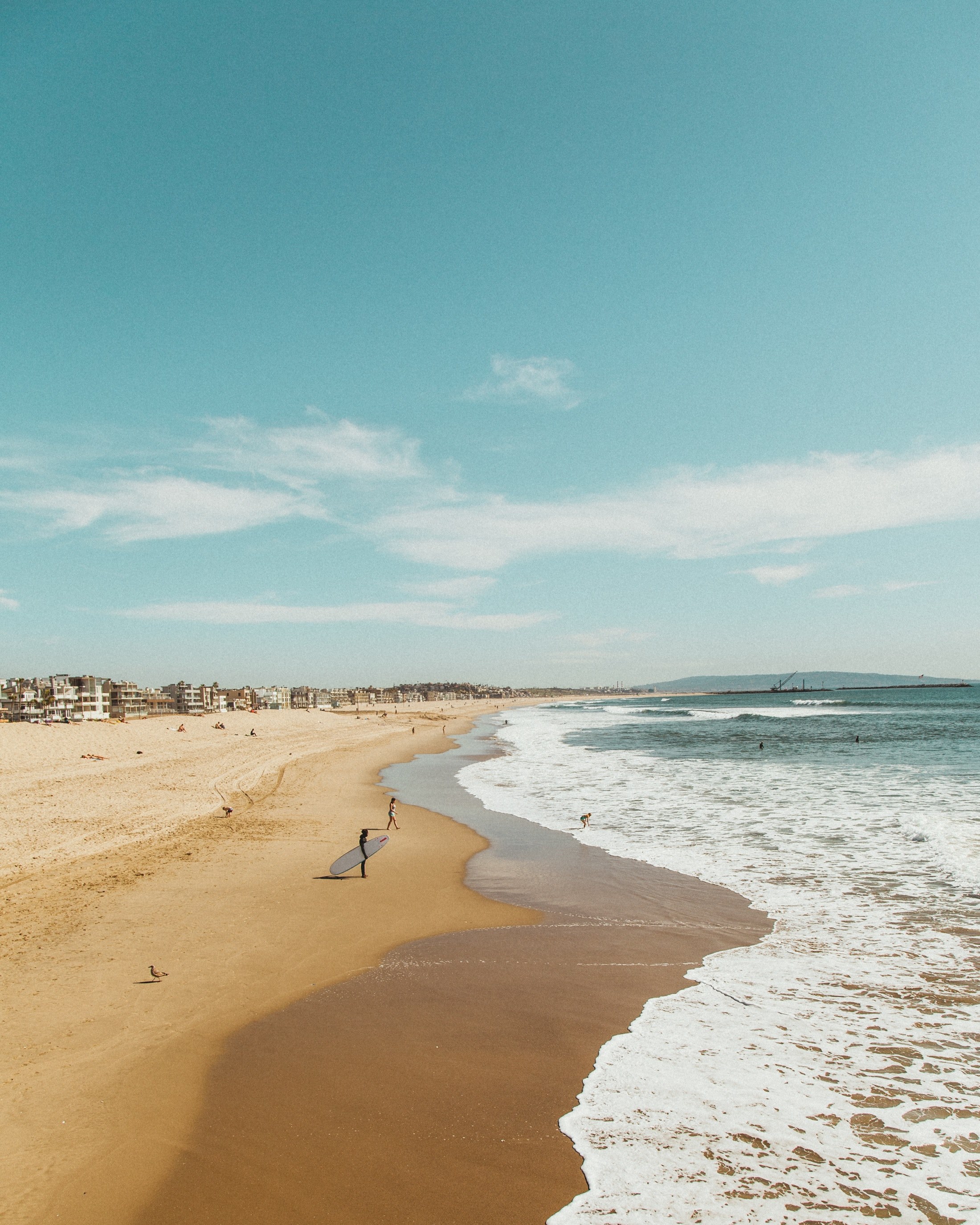 ocean foam washing on a sand beach coastline with surfers, ready for summer 4k, Phone HD Wallpaper
