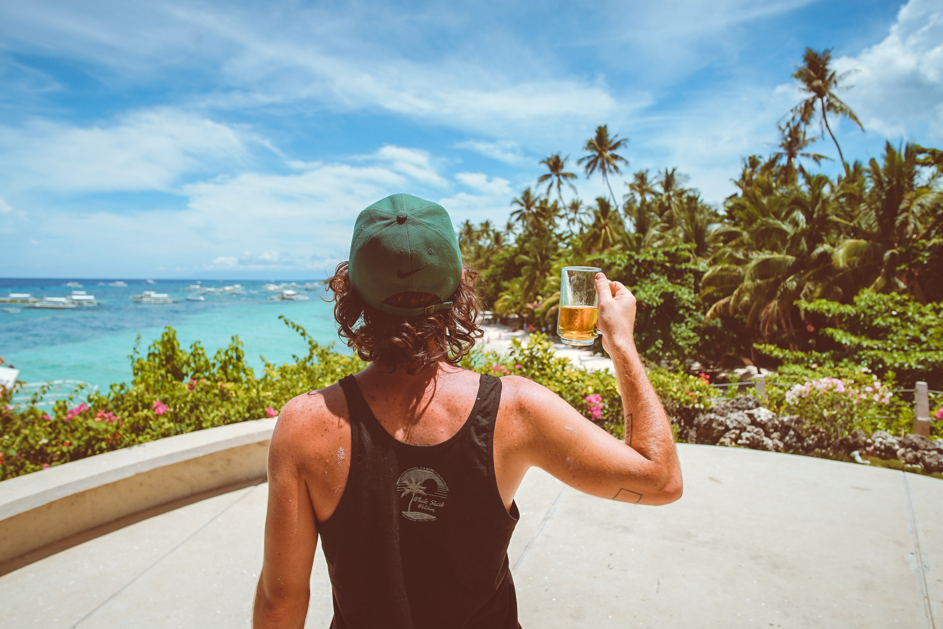 a man in a green hat holding a glass of beer on a terrace overlooking a marina, cheers mate 4k, HD Wallpaper