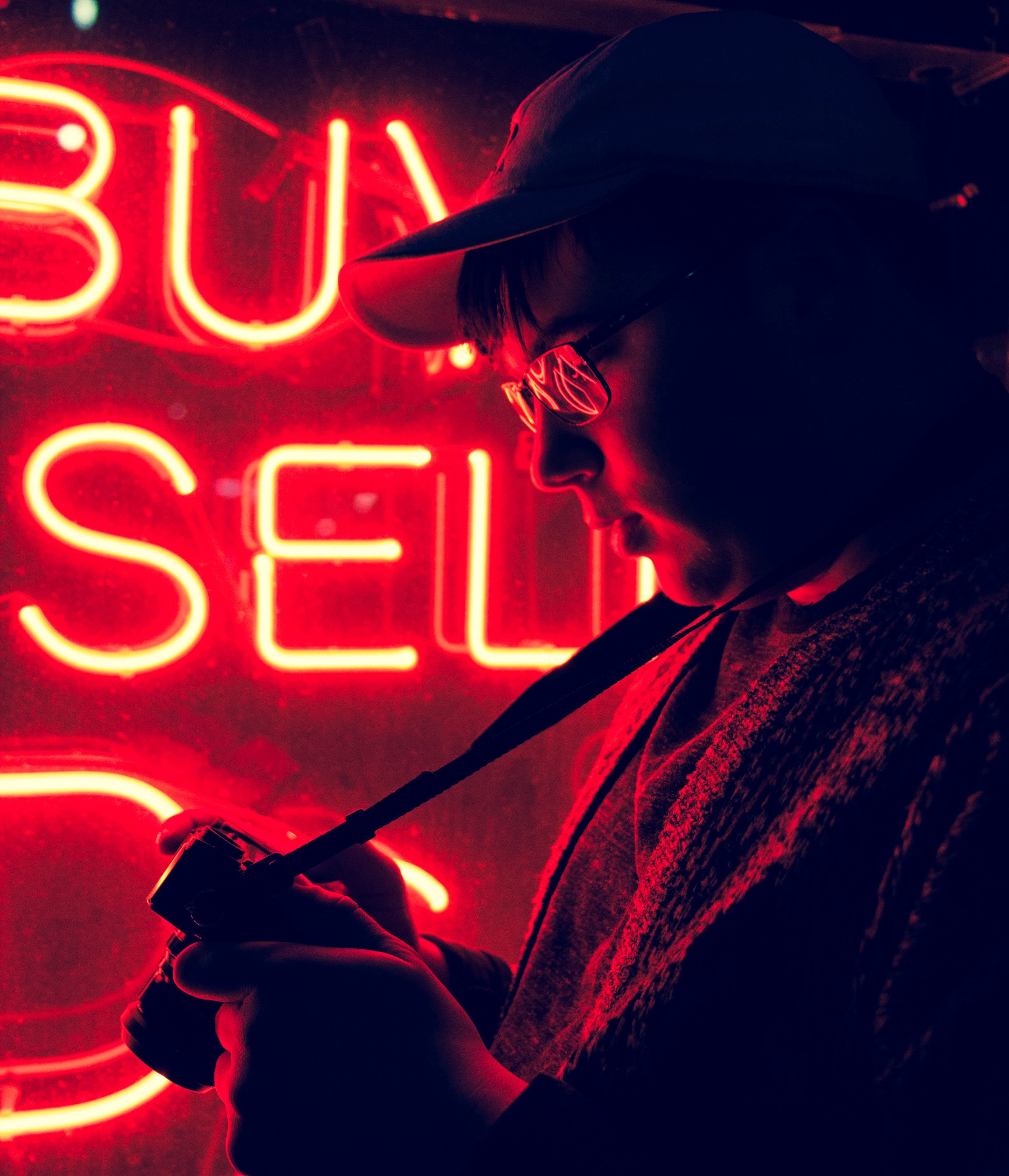 a man in glasses looking at his camera while standing near a red neon, neon_2 4k, Phone HD Wallpaper