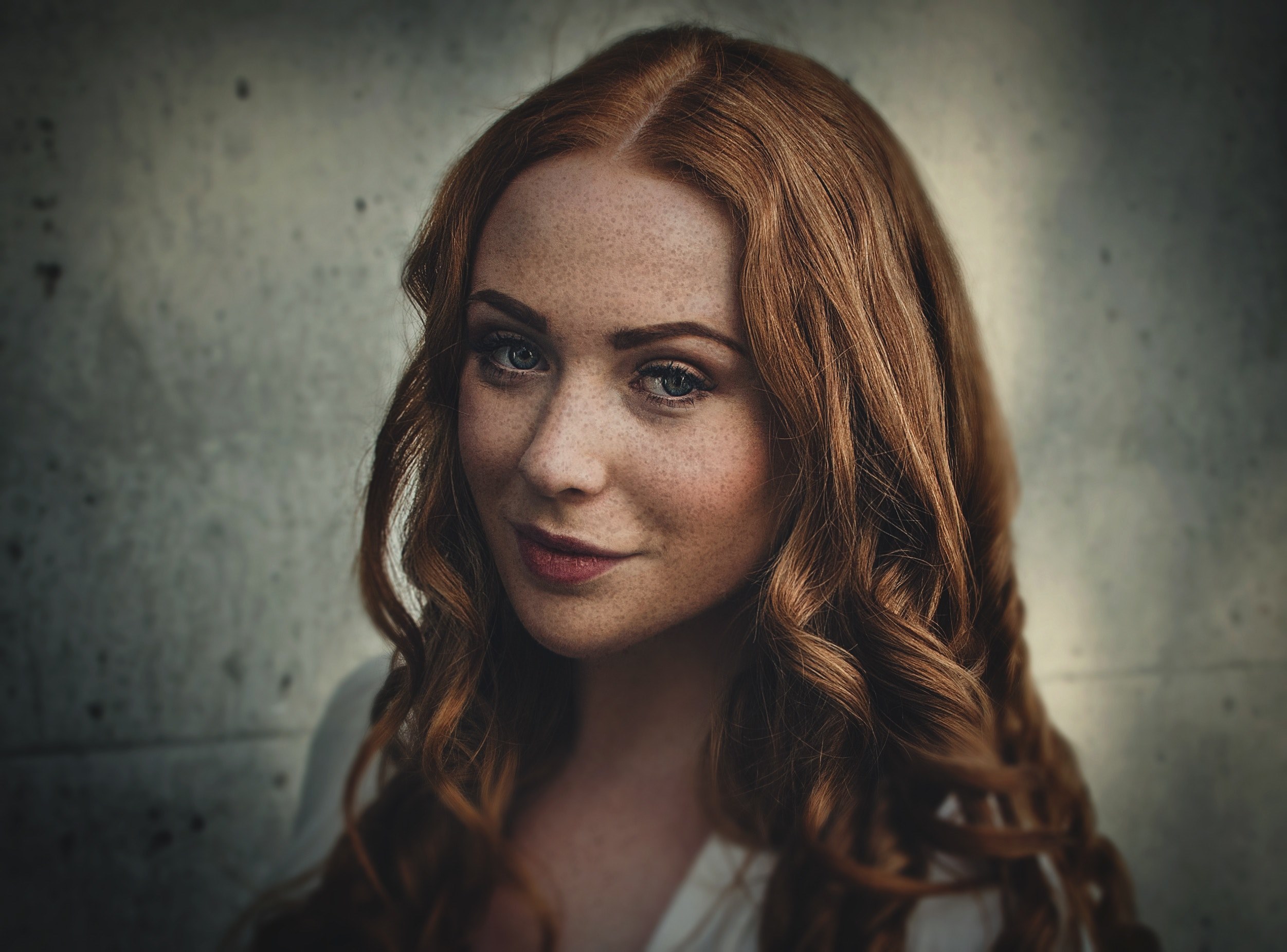 a woman with red hair freckles and crimson lipstick in front of a gray wall, freckled woman by gray wall 4k, HD Wallpaper