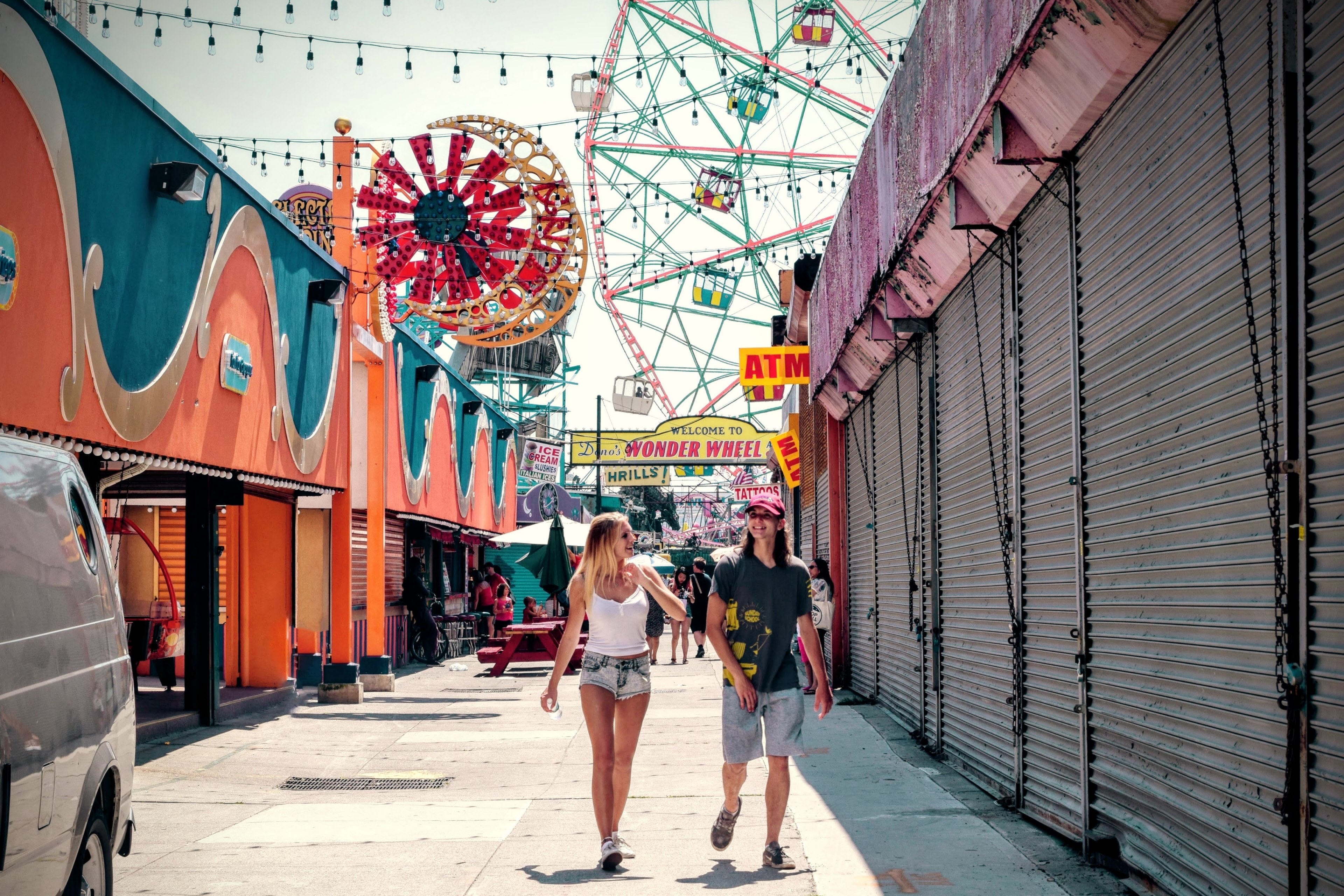 a couple walking down the boardwalk at coney island with the ferris wheel and lights behind them, coney island couple 4k, HD Wallpaper