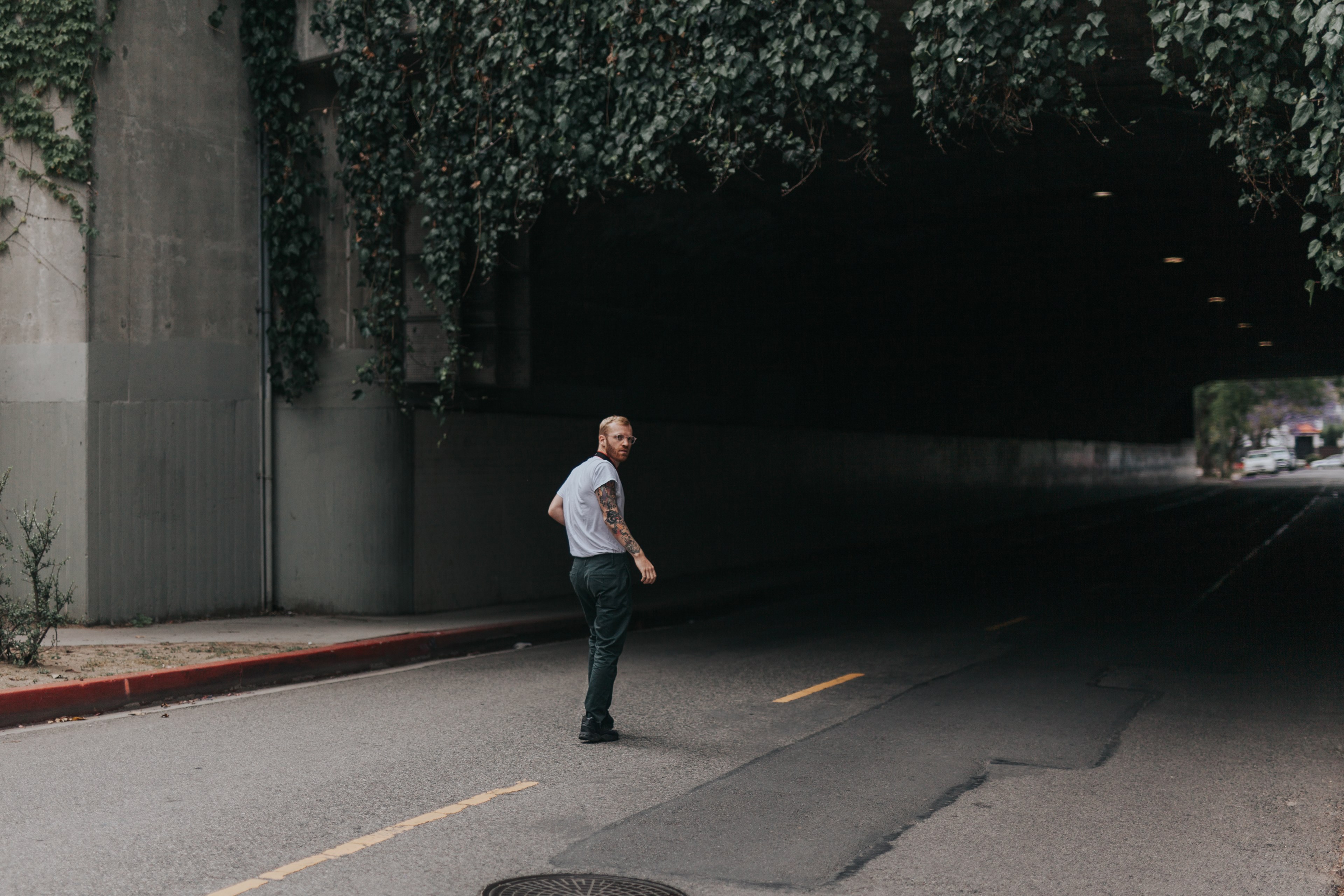 man with beard and tattoos standing in front of a tunnel road in los angeles, man walking into a tunnel 4k, HD Wallpaper