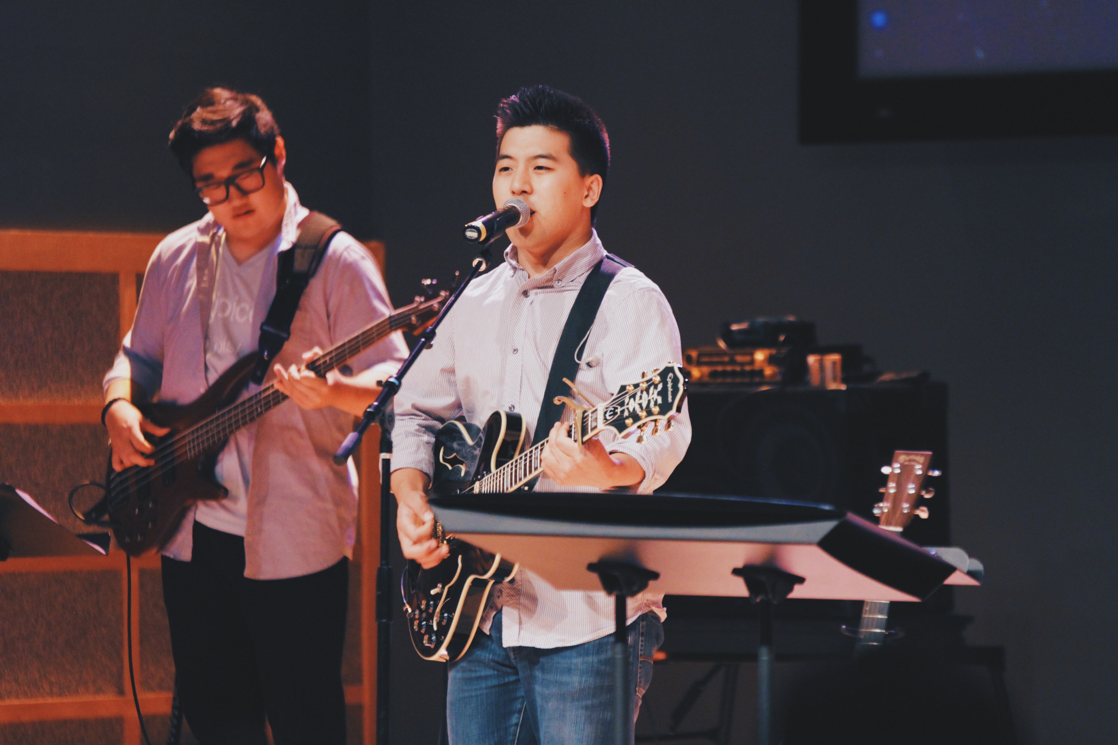 a young man playing the guitar and singing into a microphone during a live performance, young band performing 4k, HD Wallpaper