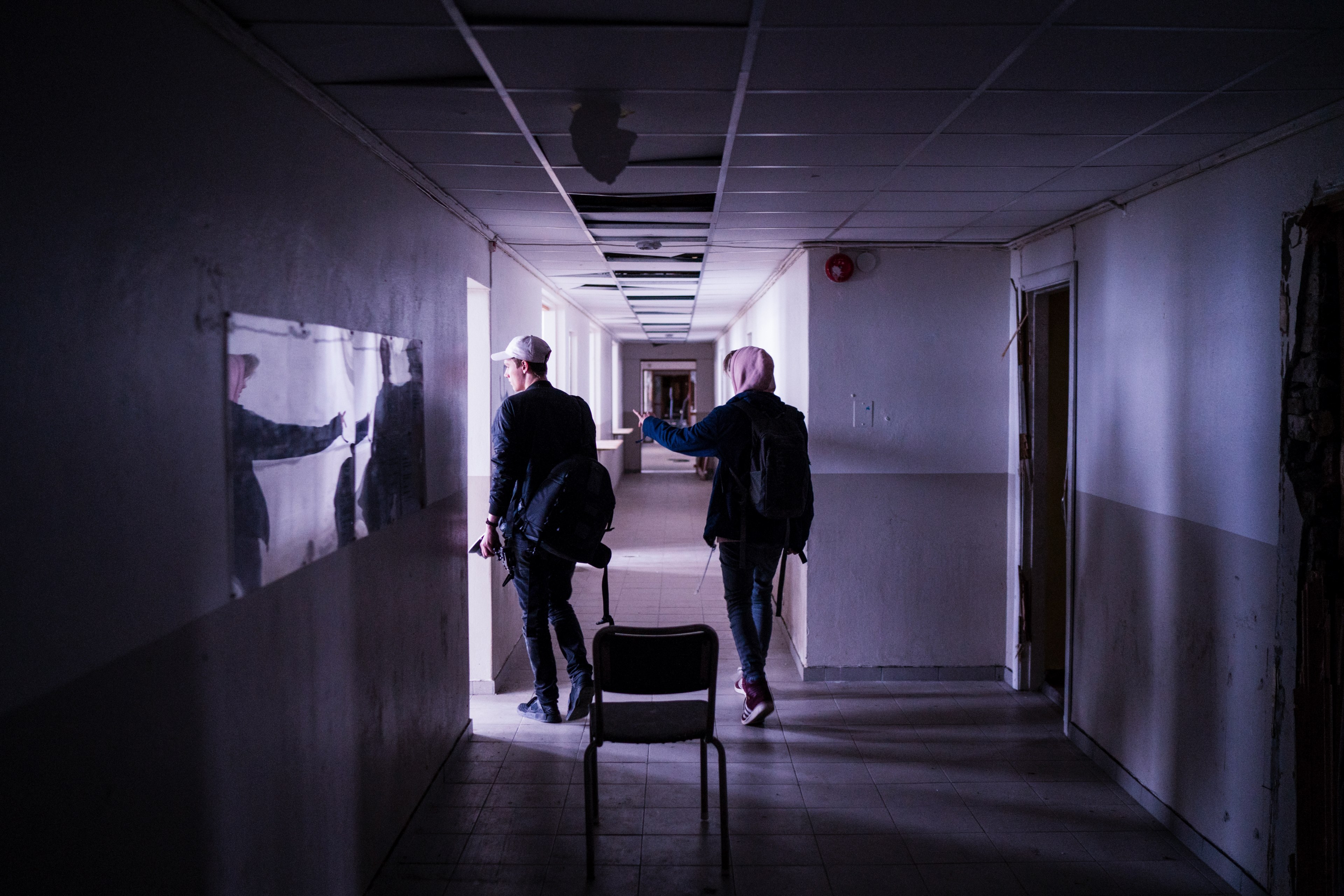 two people walk down a dimly lit white hallway with a chair in the center, two people walk down hallway 4k, HD Wallpaper
