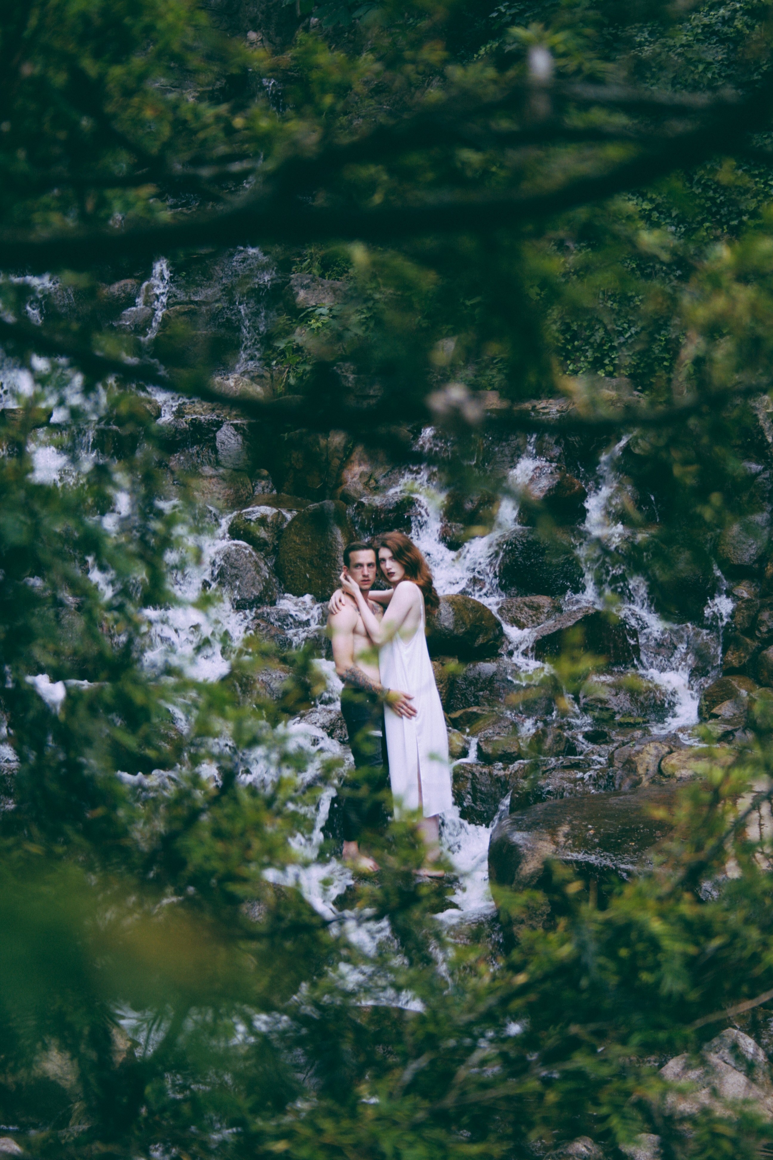a shirtless man and a woman in a dress embrace near a waterfall in the woods, _young love 4k, Phone HD Wallpaper