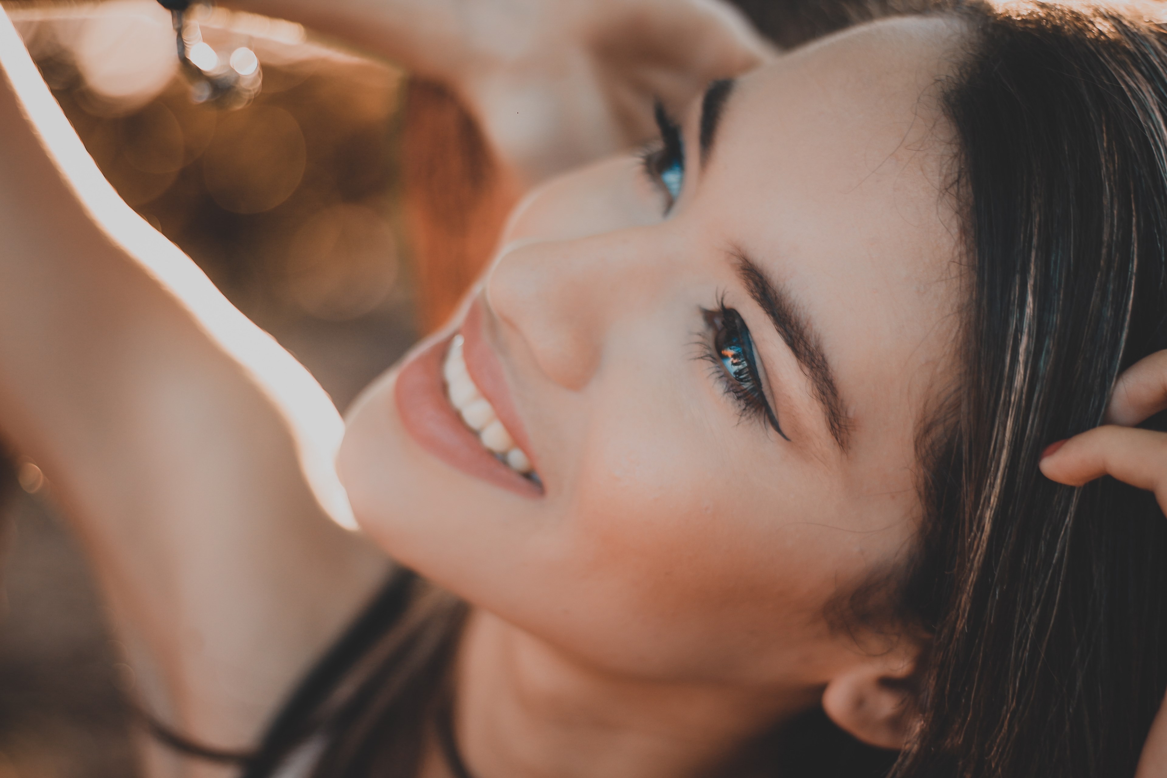 a woman in black eyeliner looks upward and smiles with her hands in her hair, smiling with hands in hair 4k, HD Wallpaper