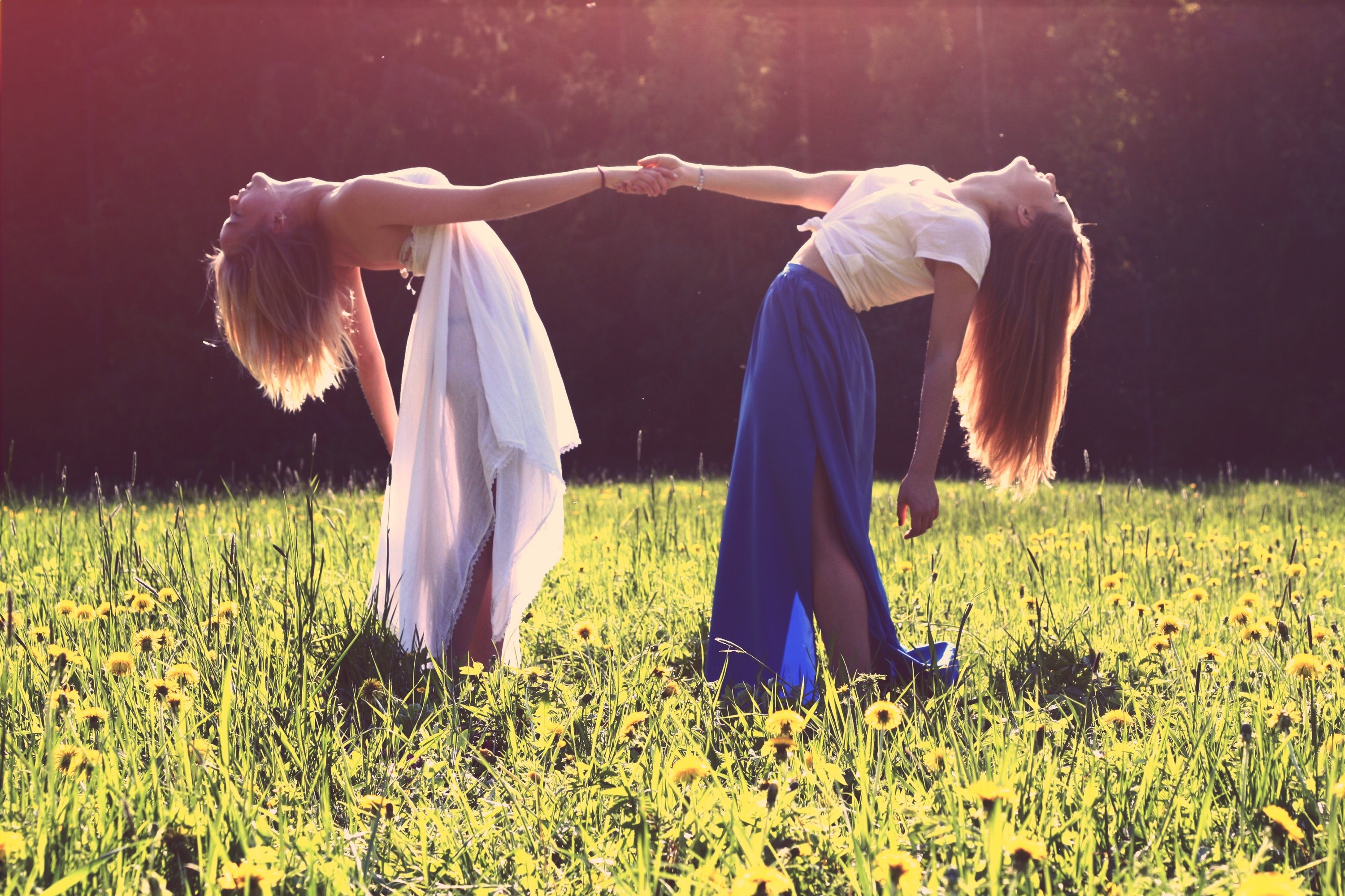 two women in dresses arching back while holding each other hands in a green meadow, two women in a meadow 4k, HD Wallpaper